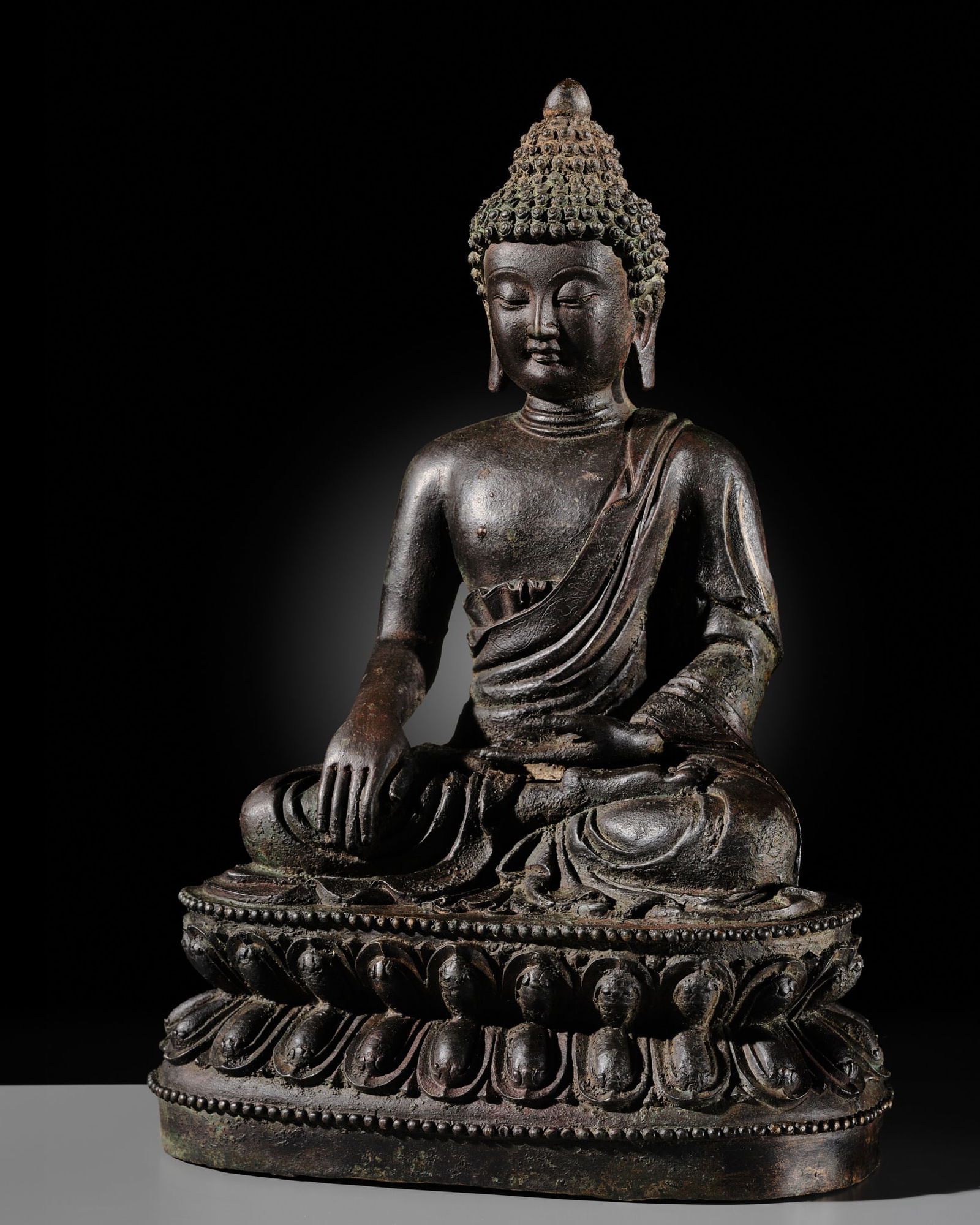A LARGE BRONZE FIGURE OF THE MEDICINE BUDDHA, BHAISHAJYAGURU, MING DYNASTY: A LARGE BRONZE FIGURE OF THE MEDICINE BUDDHA, BHAISHAJYAGURU, MING DYNASTY China, 1368-1644. Finely cast seated in dhyanasana on a double-lotus base with beaded edges, his left hand lowered in dhyana