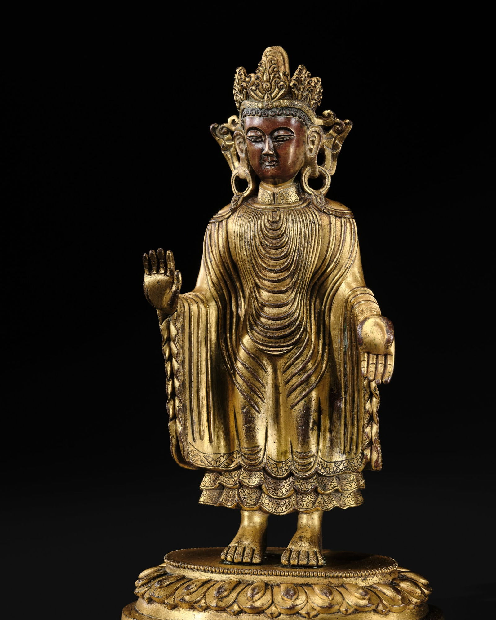 A RARE UDAYANA-STYLE GILT-BRONZE FIGURE OF GAUTAMA BUDDHA, QING DYNASTY, 18TH CENTURY: A RARE UDAYANA-STYLE GILT-BRONZE FIGURE OF GAUTAMA BUDDHA, QING DYNASTY, 18TH CENTURY Finely cast standing with the right and left hands held in abhaya and varada mudra respectively, the body envelope