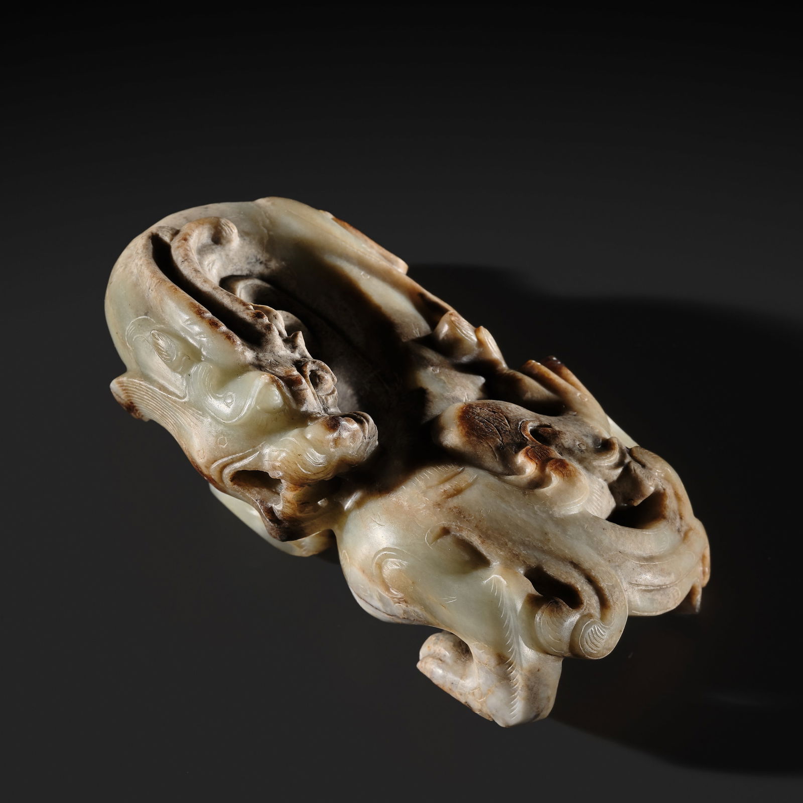 AN EXCEPTIONAL AND POWERFULLY CARVED WHITE AND BROWN JADE CARVING OF A BIXIE, WESTERN HAN DYNASTY: AN EXCEPTIONAL AND POWERFULLY CARVED WHITE AND BROWN JADE CARVING OF A BIXIE, WESTERN HAN DYNASTY China, 206-8 BC. Superbly carved in the round, the mythical creature depicted in an animated pose, pro