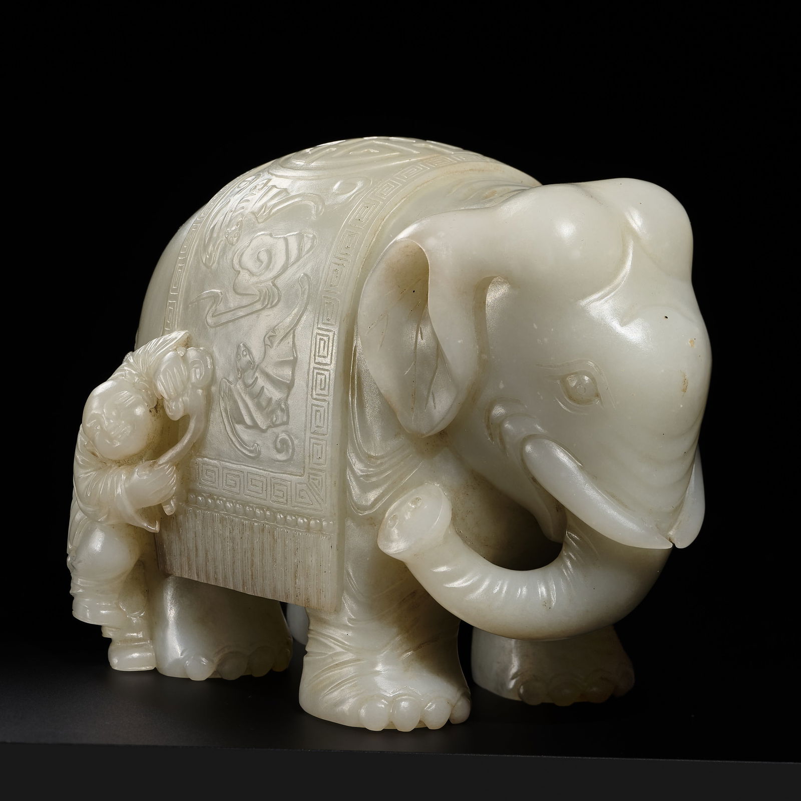 A LARGE WHITE JADE FIGURE OF AN ELEPHANT AND A BOY, 18TH CENTURY: A LARGE WHITE JADE FIGURE OF AN ELEPHANT AND A BOY, 18TH CENTURY China. Skillfully worked to depict a standing elephant, the animal's body rendered with characteristic folds of wrinkles and terminatin
