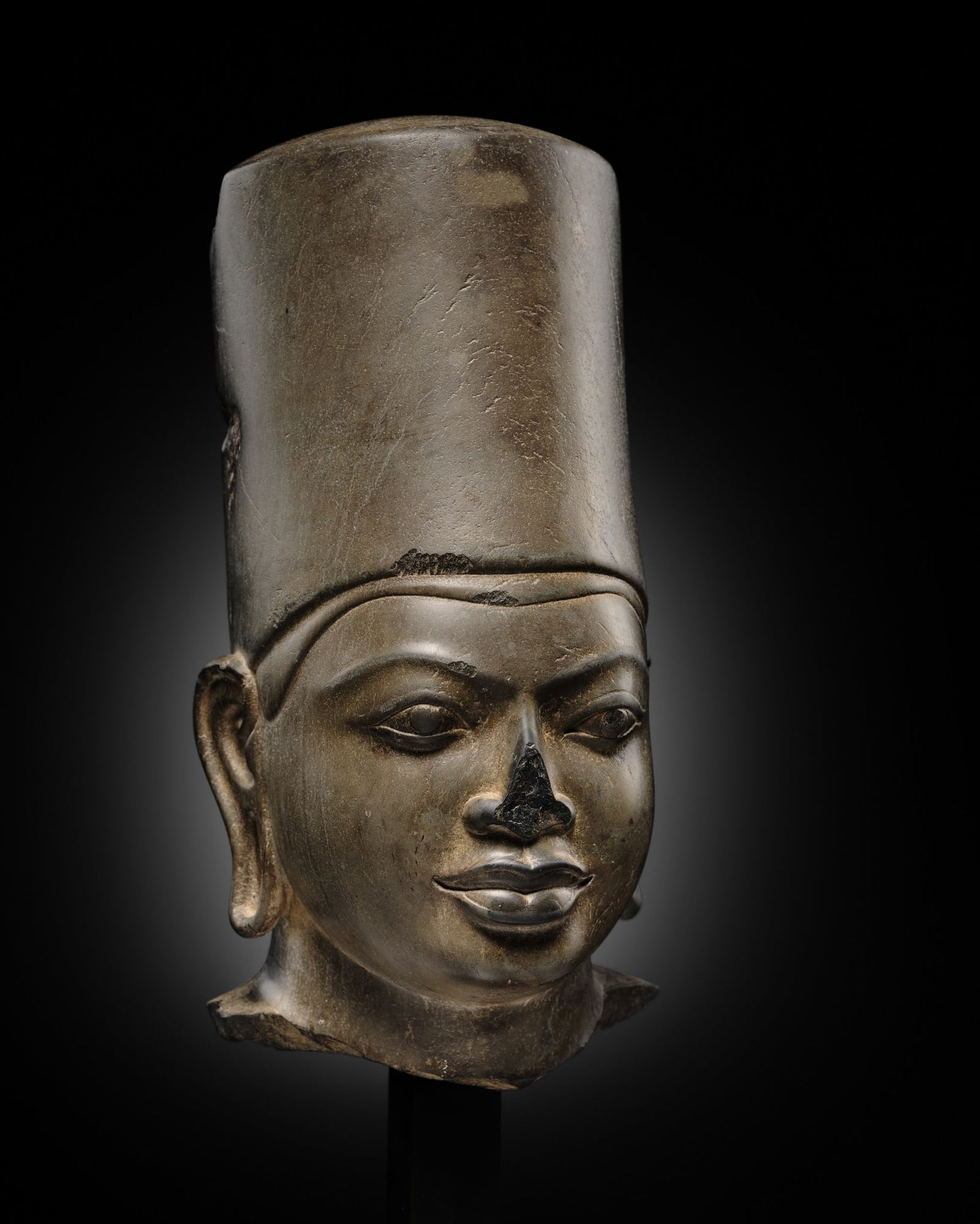 A POLISHED SANDSTONE HEAD OF VISHNU, PRE-ANGKOR PERIOD, PRASAT ANDET STYLE, 7TH CENTURY: A POLISHED SANDSTONE HEAD OF VISHNU, PRE-ANGKOR PERIOD, PRASAT ANDET STYLE, 7TH CENTURY Finely carved, with double-lined bow-shaped lips set beneath a broad nose, elongated almond-shaped eyes with inc