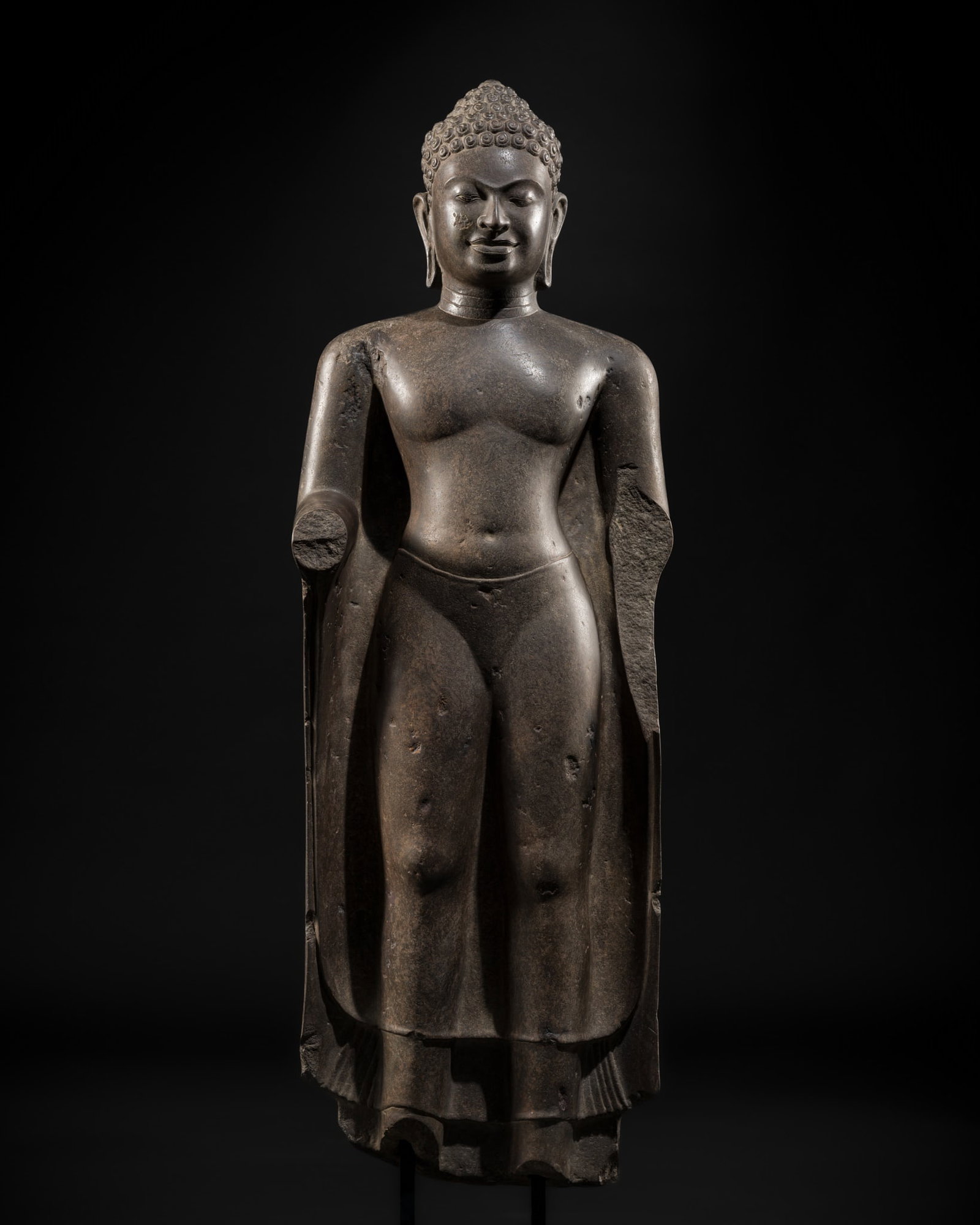 A POLISHED SANDSTONE FIGURE OF BUDDHA, MON DVARAVATI PERIOD, 7TH-9TH CENTURY: A POLISHED SANDSTONE FIGURE OF BUDDHA, MON DVARAVATI PERIOD, 7TH-9TH CENTURY Thailand, 8th-9th century. Finely sculpted and sensitively carved, standing in samabhanga with his right hand raised. Weari