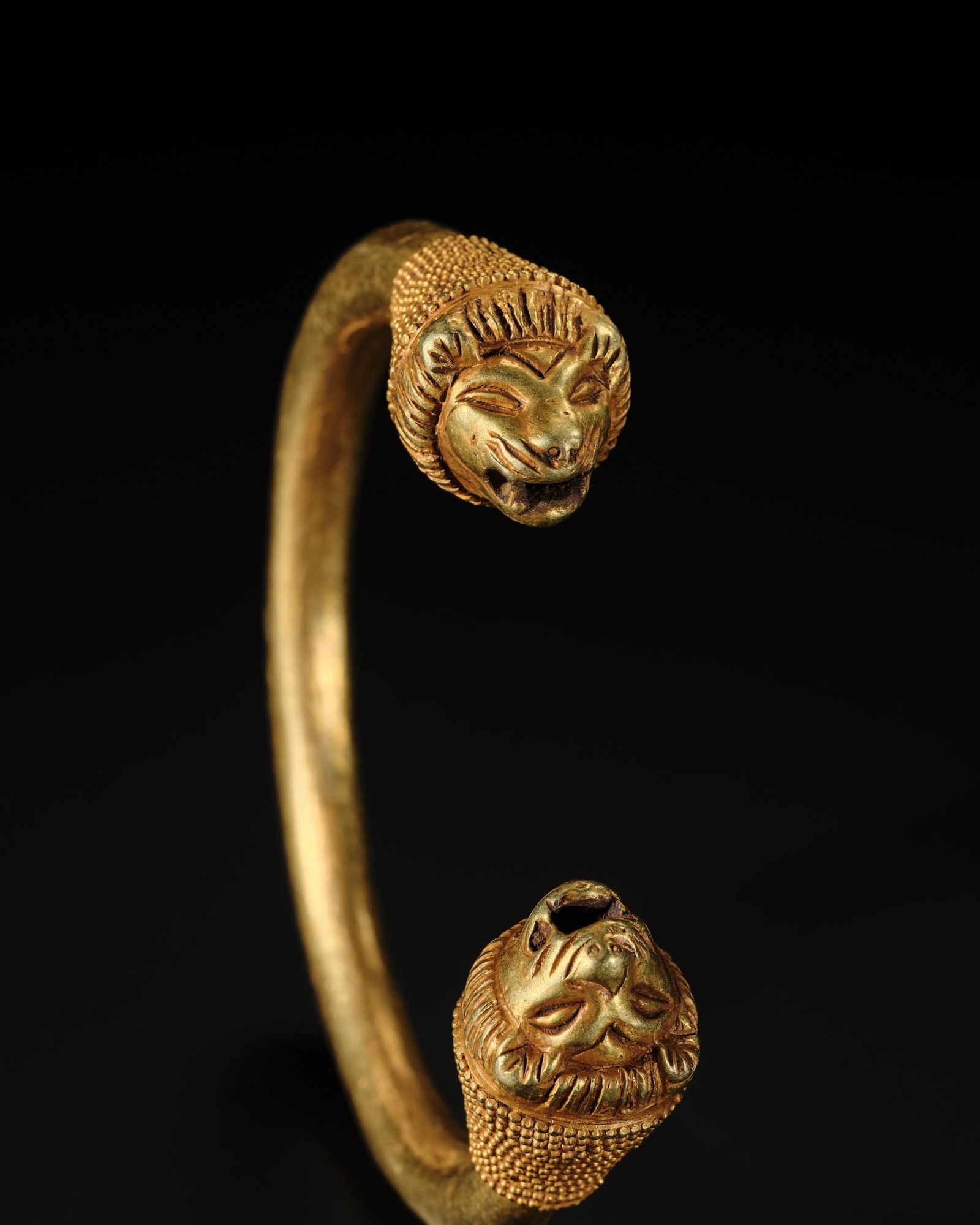 A WESTERN ASIATIC GOLD BRACELET WITH LION-HEADED TERMINALS, CIRCA 8TH-6TH CENTURY BC: A WESTERN ASIATIC GOLD BRACELET WITH LION-HEADED TERMINALS, CIRCA 8TH-6TH CENTURY BC Of penannular form, the bracelet features lion-headed terminals with gently protruding ears, finely detailed facial