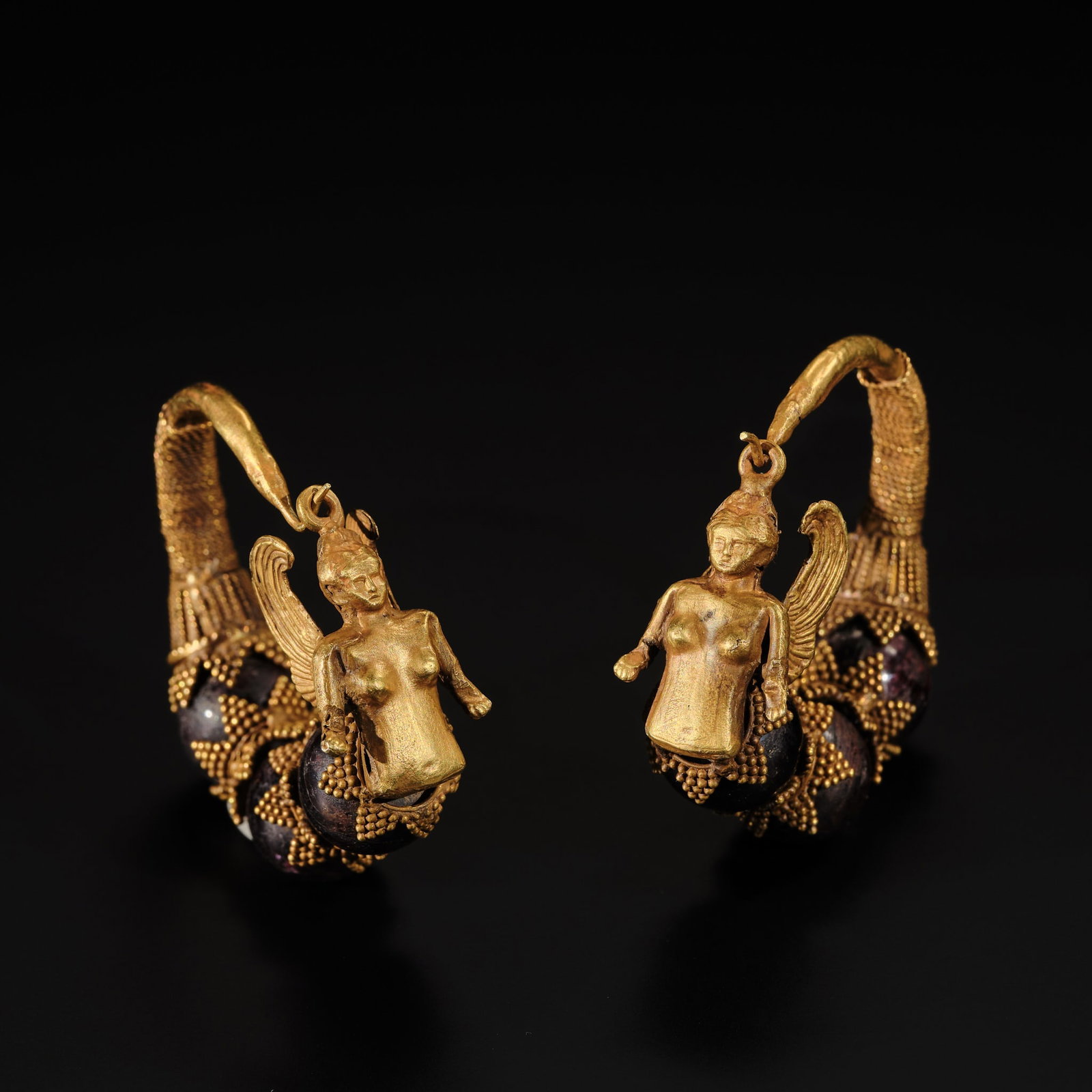 A PAIR OF GREEK GOLD AND GARNET 'SIREN' EARRINGS, HELLENISTIC PERIOD, CIRCA 4TH-3RD CENTURY BC: A PAIR OF GREEK GOLD AND GARNET 'SIREN' EARRINGS, HELLENISTIC PERIOD, CIRCA 4TH-3RD CENTURY BC Each of hoop form, with a spiraling wire tapering to a plain wire, set with three globular garnets inters
