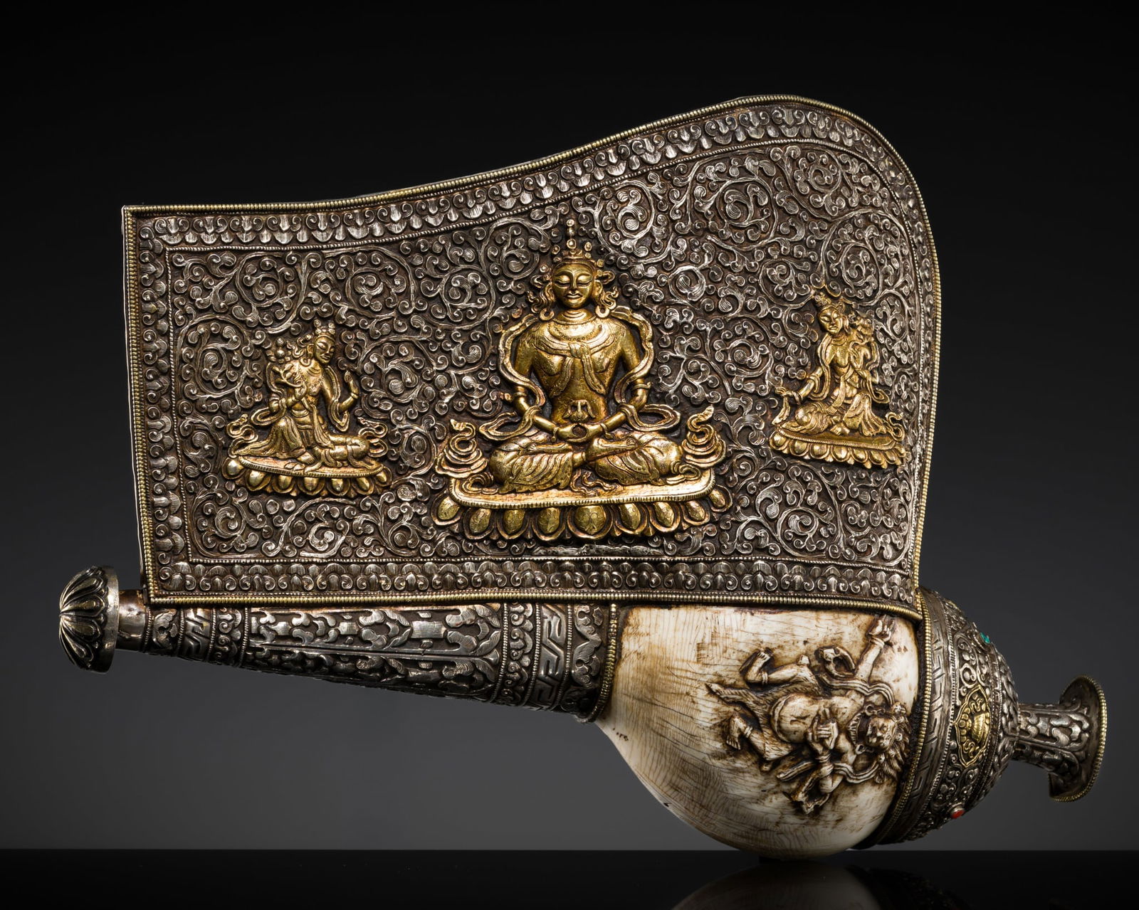 A CARVED CONCH-SHELL TRUMPET, DUNG DKAR, WITH A PARCEL-GILT SILVER REPOUSSÉ MOUNT DEPICTING: A CARVED CONCH-SHELL TRUMPET, DUNG DKAR, WITH A PARCEL-GILT SILVER REPOUSSÉ MOUNT DEPICTING AMITAYUS, 17TH-18TH CENTURY Tibet. The white shell carved in high relief with a wrathful Dharmapala sta