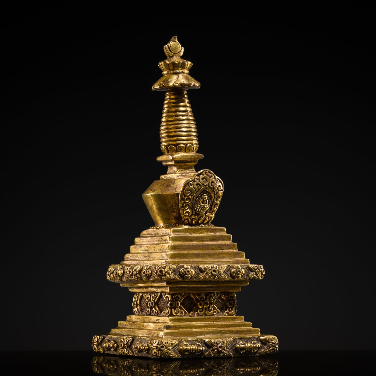 A GILT BRONZE STUPA, TIBET, 18TH CENTURY: A GILT BRONZE STUPA, TIBET, 18TH CENTURY The tiered parasol rises from a domed midsection set to the front with a niche framing Amitabha, and is surmounted by a finial of sun and moon discs. It stands