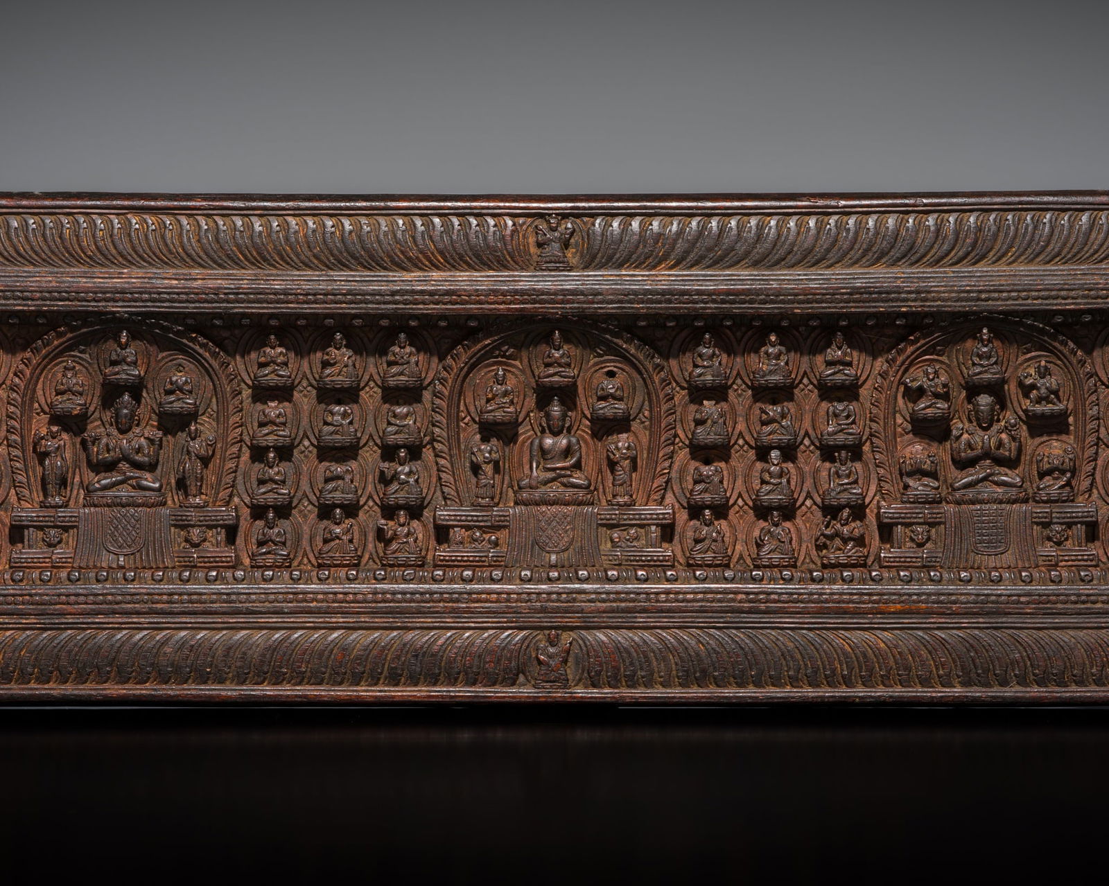 A WOOD MANUSCRIPT COVER WITH BUDDHA SHAKYAMUNI, TIBET, 14TH-15TH CENTURY: A WOOD MANUSCRIPT COVER WITH BUDDHA SHAKYAMUNI, TIBET, 14TH-15TH CENTURY Finely carved in deep relief with Buddha Shakyamuni seated at the center in dhyanasana, his right hand lowered in bhumisparsha