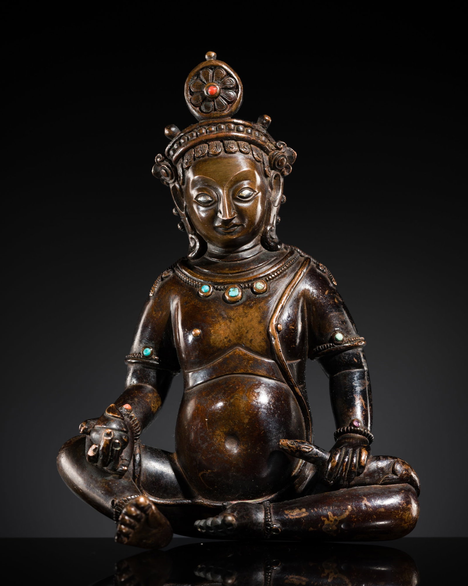 A SILVER-INLAID BRONZE FIGURE OF JAMBHALA, TIBET, 18TH-19TH CENTURY: A SILVER-INLAID BRONZE FIGURE OF JAMBHALA, TIBET, 18TH-19TH CENTURY Heavily cast, the figure seated in a relaxed pose, the hands resting on the bent knees and holding the lemon-fruit in his right hand