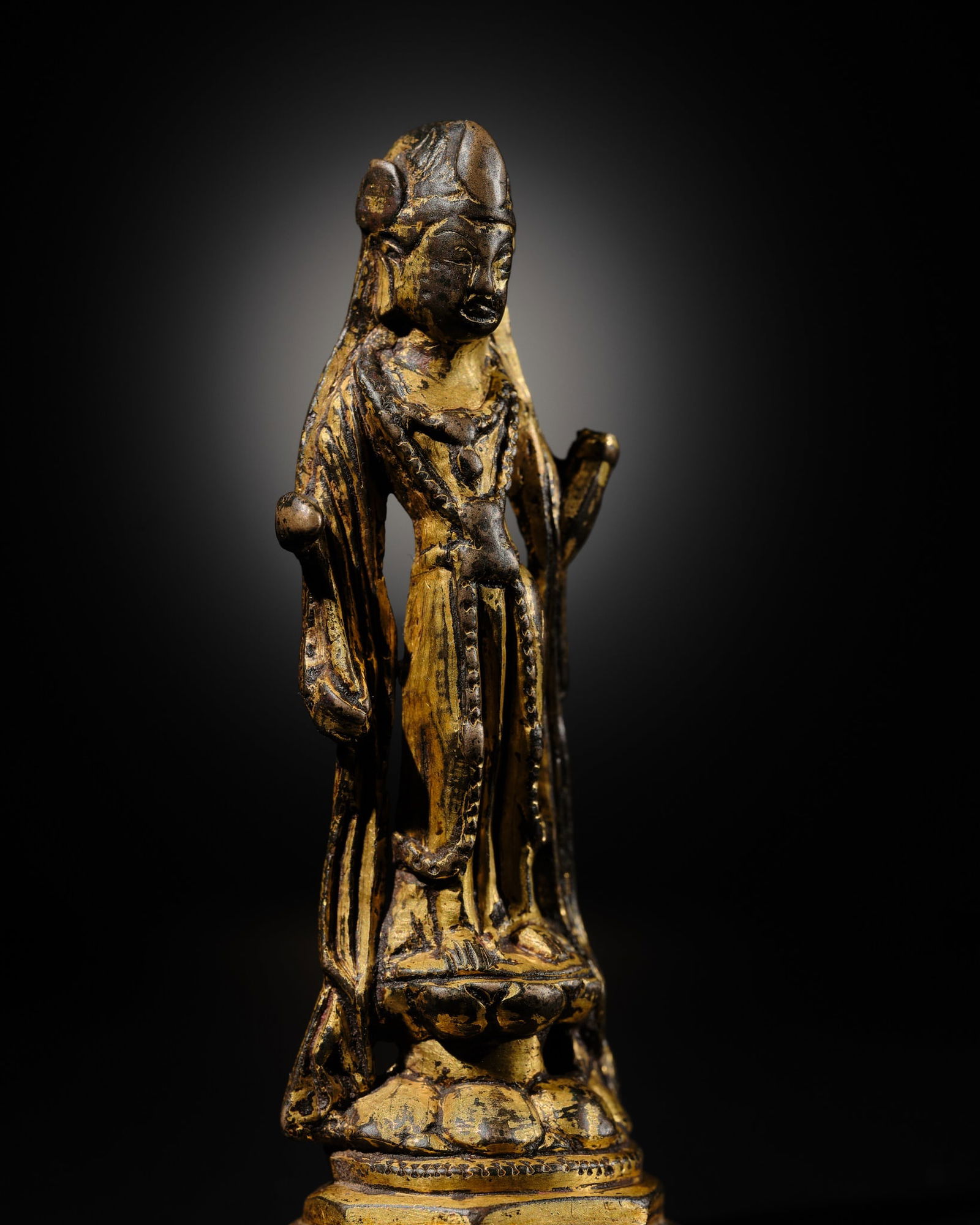 A GILT-BRONZE FIGURE OF A BODHISATTVA, SUI TO EARLY TANG DYNASTY: A GILT-BRONZE FIGURE OF A BODHISATTVA, SUI TO EARLY TANG DYNASTY China, 7th century. Sensitively cast standing on a hollow double-lotus base raised on an octagonal tiered plinth, wearing an elaborate
