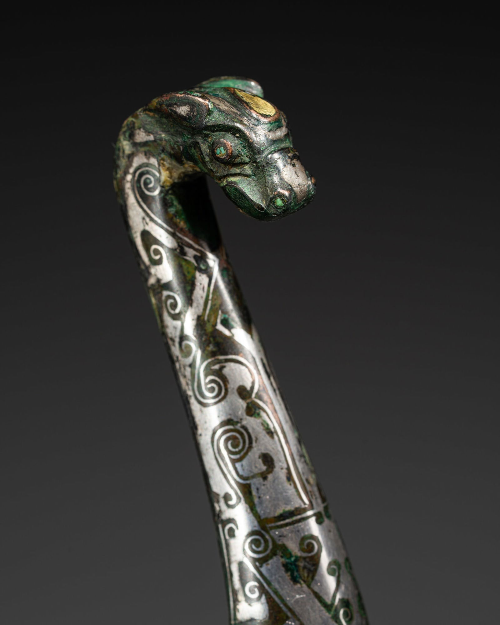 A SUPERB TURQUOISE, GOLD, SILVER, AND COPPER-INLAID BRONZE GARMENT HOOK, DAIGOU: A SUPERB TURQUOISE, GOLD, SILVER, AND COPPER-INLAID BRONZE GARMENT HOOK, DAIGOU Expert's note: Bronze garment hooks from the Warring States and early Han periods are well known for their refined metal