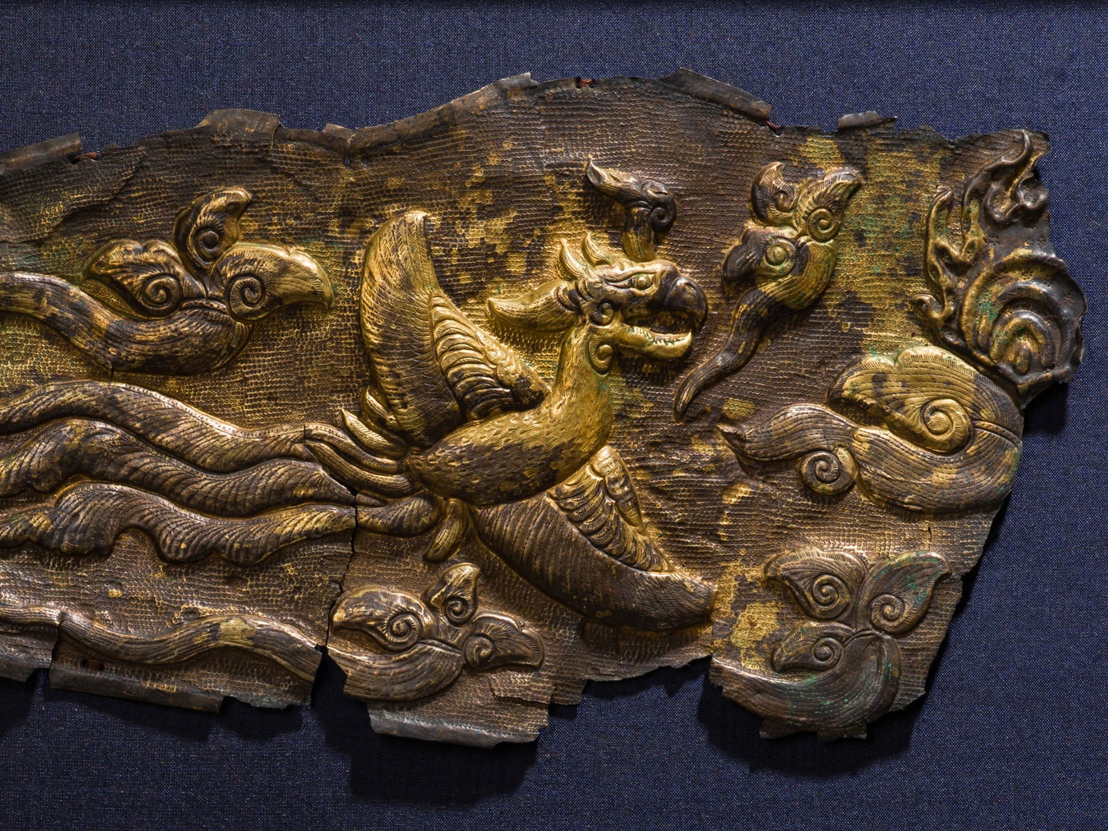 A GILT-SILVER REPOUSSÉ 'PHOENIX' FRAGMENT, LIAO DYNASTY: A GILT-SILVER REPOUSSÉ 'PHOENIX' FRAGMENT, LIAO DYNASTY China, 916-1125. Finely embossed, chased, and neatly incised to depict a phoenix in flight with outstretched wings and intricately worked f