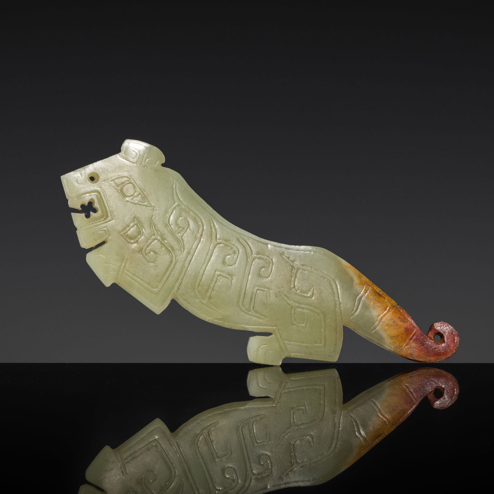 A PALE GREEN AND RUSSET JADE 'TIGER' PENDANT, WESTERN ZHOU DYNASTY (1 of 10)
