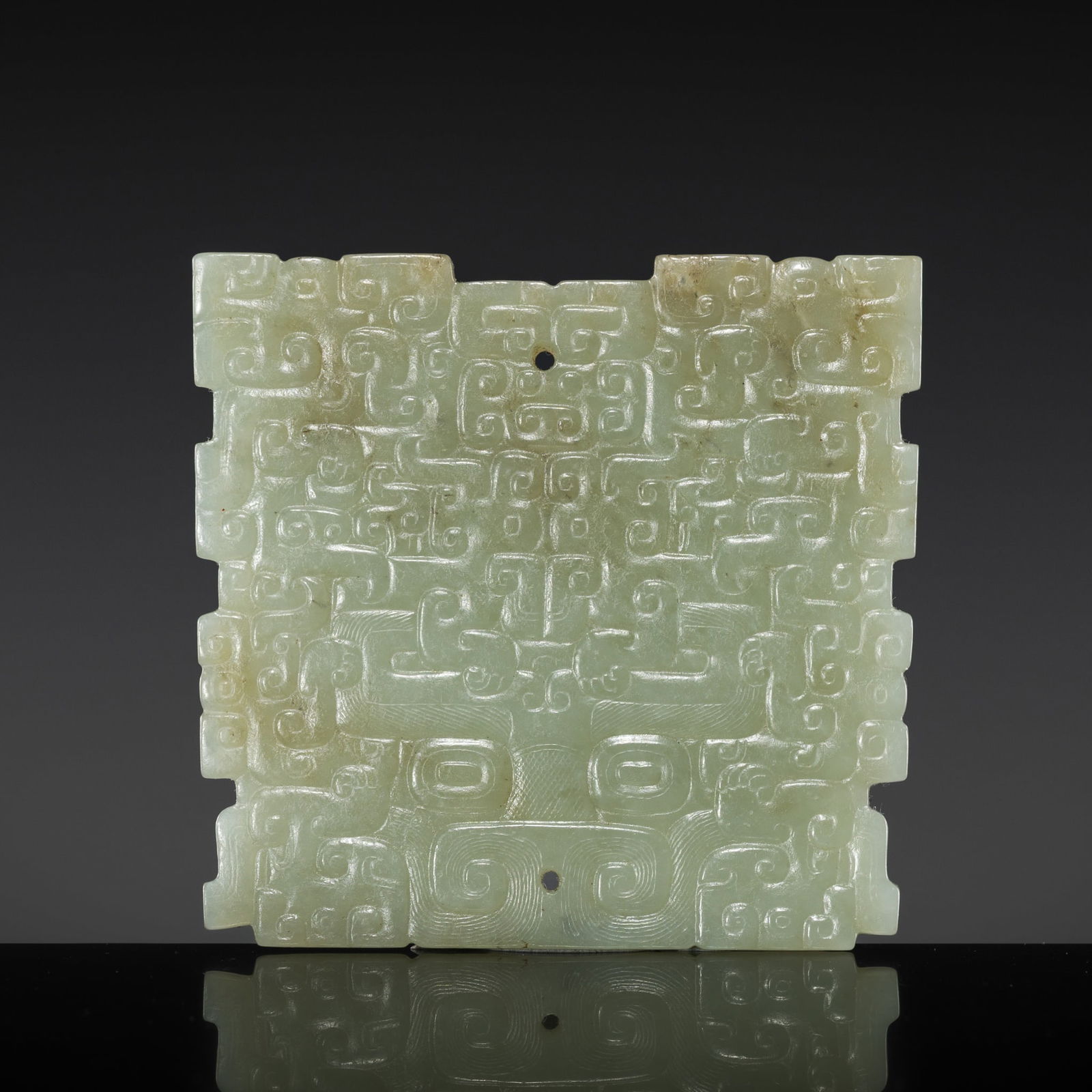 A PALE GREEN JADE 'BOVINE' MASK, SPRING AND AUTUMN PERIOD: A PALE GREEN JADE 'BOVINE' MASK, SPRING AND AUTUMN PERIOD China, 6th-5th century BC. Of square form with notched edges, finely carved to one side in shallow relief with the horns, eyes, and nose of a