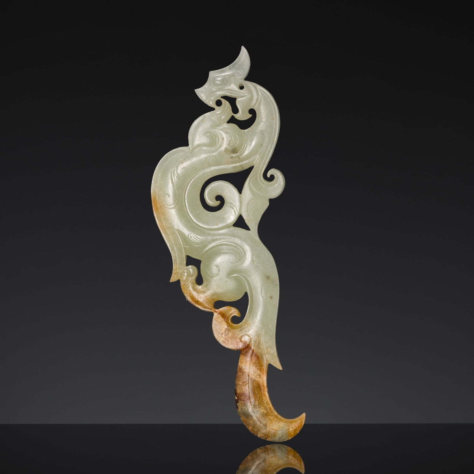 A WHITE AND RUSSET JADE DRAGON PENDANT, XI, LATE WARRING STATES PERIOD TO EARLY WESTERN HAN DYNASTY: A WHITE AND RUSSET JADE DRAGON PENDANT, XI, LATE WARRING STATES PERIOD TO EARLY WESTERN HAN DYNASTY China, circa 3rd century BC. The flat ornament is finely carved in openwork as a horned dragon, its