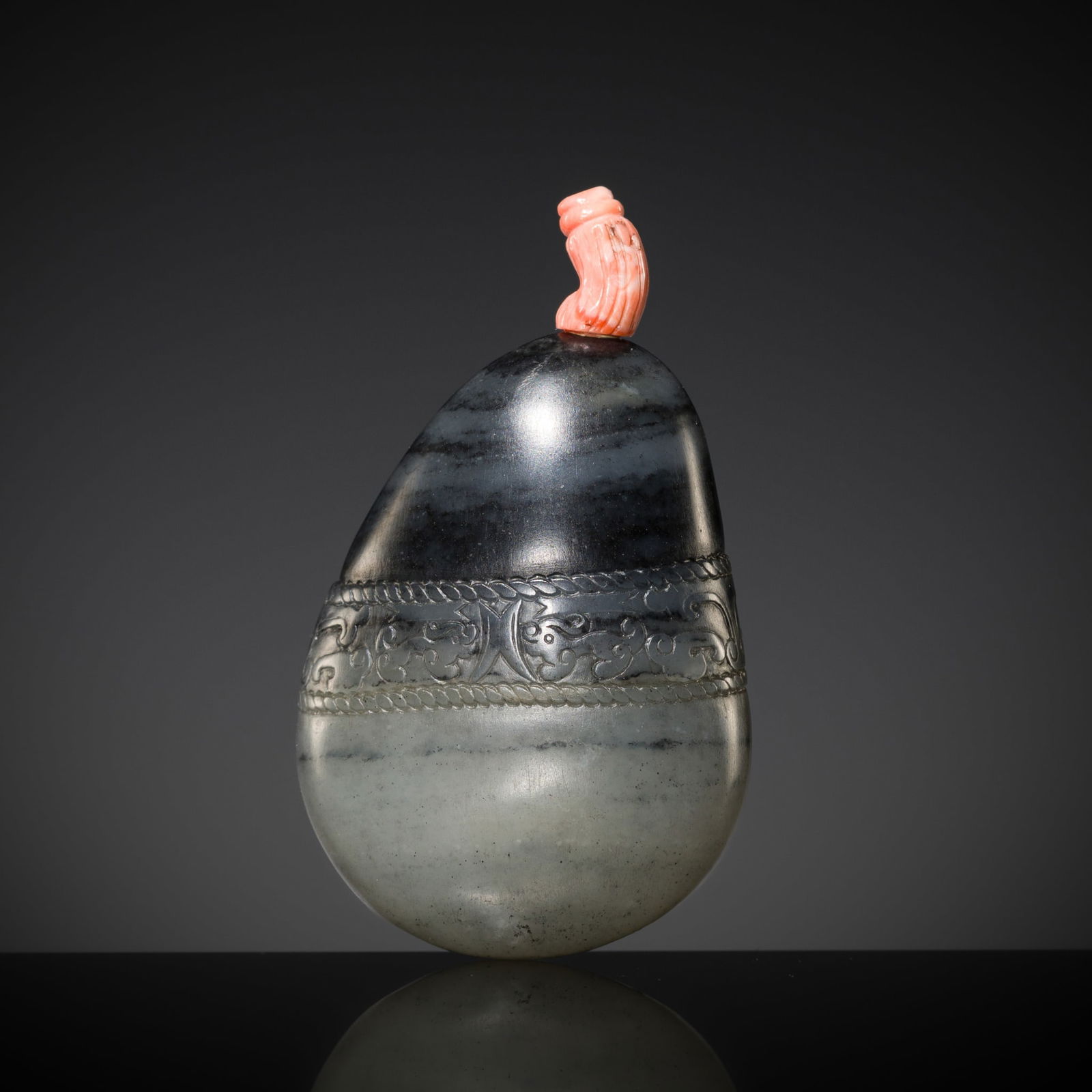A BLACK AND WHITE JADE 'CHILONG AND TAOTIE' SNUFF BOTTLE, 18TH CENTURY: A BLACK AND WHITE JADE 'CHILONG AND TAOTIE' SNUFF BOTTLE, 18TH CENTURY China. Well hollowed with thin walls, of natural pebble form, finely incised at the mid-section with a band of chilong and archai