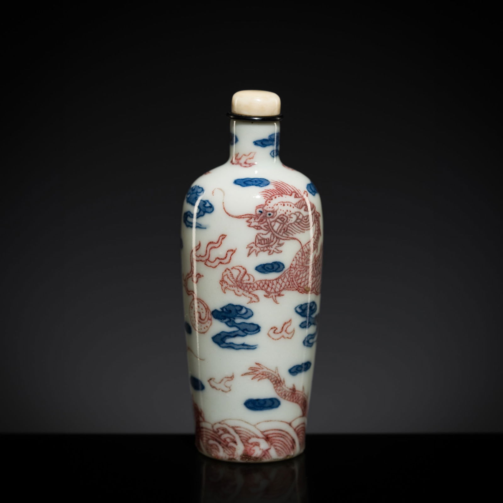 A COPPER-RED AND COBALT-BLUE 'DRAGONS' SNUFF BOTTLE, 1830-1890: A COPPER-RED AND COBALT-BLUE 'DRAGONS' SNUFF BOTTLE, 1830-1890 China. Of cylindrical form, tapering towards the foot, and surmounted by a thin, tubular neck. The exterior finely painted in copper-red