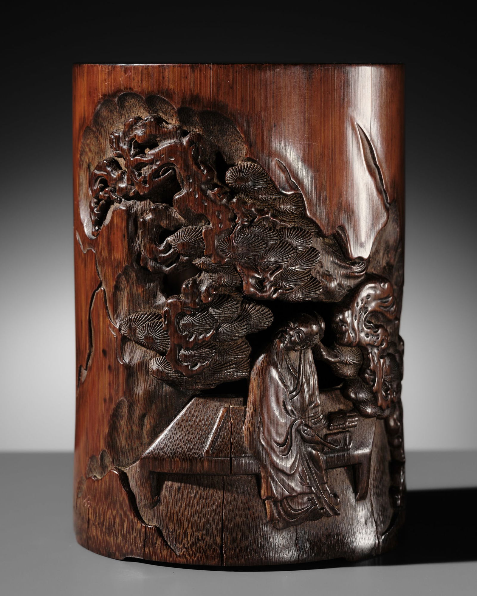 A BAMBOO 'SCHOLAR AND PINE' BRUSHPOT, BITONG, LATE QING DYNASTY TO REPUBLIC PERIOD: A BAMBOO 'SCHOLAR AND PINE' BRUSHPOT, BITONG, LATE QING DYNASTY TO REPUBLIC PERIOD China, 19th to early 20th century. Carved in high relief, the brush pot depicts a solitary scholar standing in front