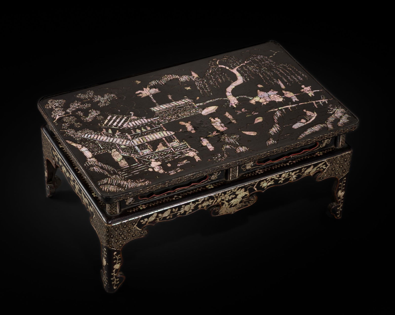 A MOTHER-OF-PEARL-INLAID BLACK LACQUER LOW TABLE, KANGJI, 17TH CENTURY: A MOTHER-OF-PEARL-INLAID BLACK LACQUER LOW TABLE, KANGJI, 17TH CENTURY China. The rectangular top finely inlaid in mother-of-pearl with figures set in a pavilion complex along a riverbank, framed to o