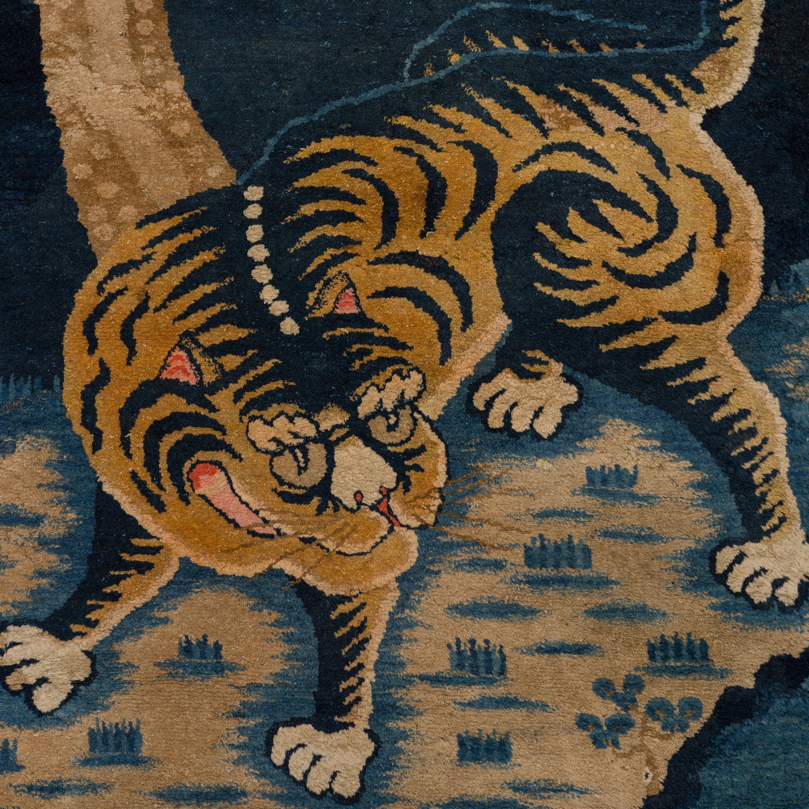 A 'STALKING TIGER' WOOL RUG, HIMALAYAN REGION, LATE 19TH TO EARLY 20TH CENTURY: A 'STALKING TIGER' WOOL RUG, HIMALAYAN REGION, LATE 19TH TO EARLY 20TH CENTURY Finely woven with a tiger menacingly crouching low, its tail raised and waving in the air, under the shade of a pine tree