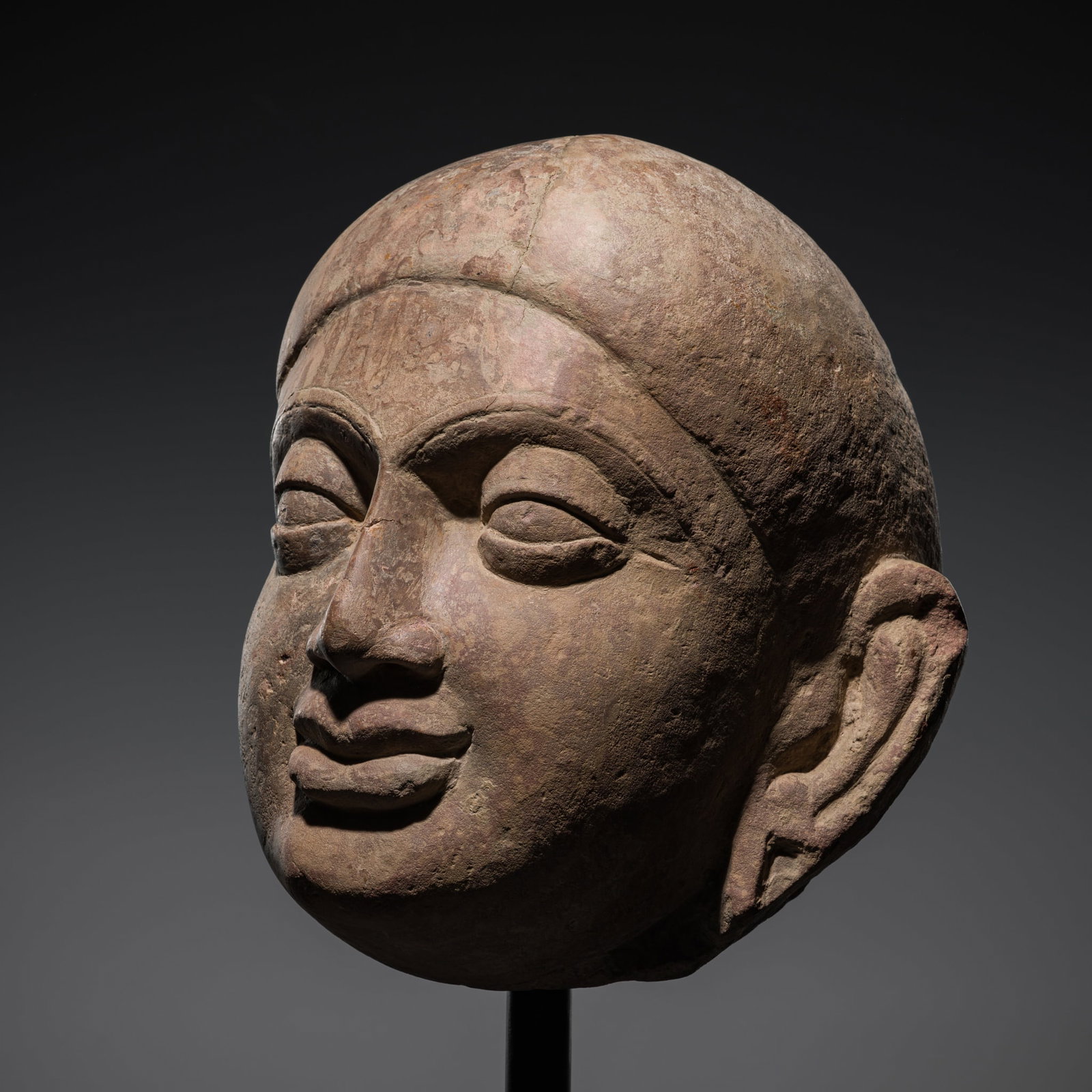 A RED SANDSTONE HEAD OF BUDDHA, MATHURA, KUSHAN PERIOD, 2ND-3RD CENTURY: A RED SANDSTONE HEAD OF BUDDHA, MATHURA, KUSHAN PERIOD, 2ND-3RD CENTURY India, Uttar Pradesh. Superbly carved with the bold, over-sized features characteristic of the Kushan period, the ascetic's comp