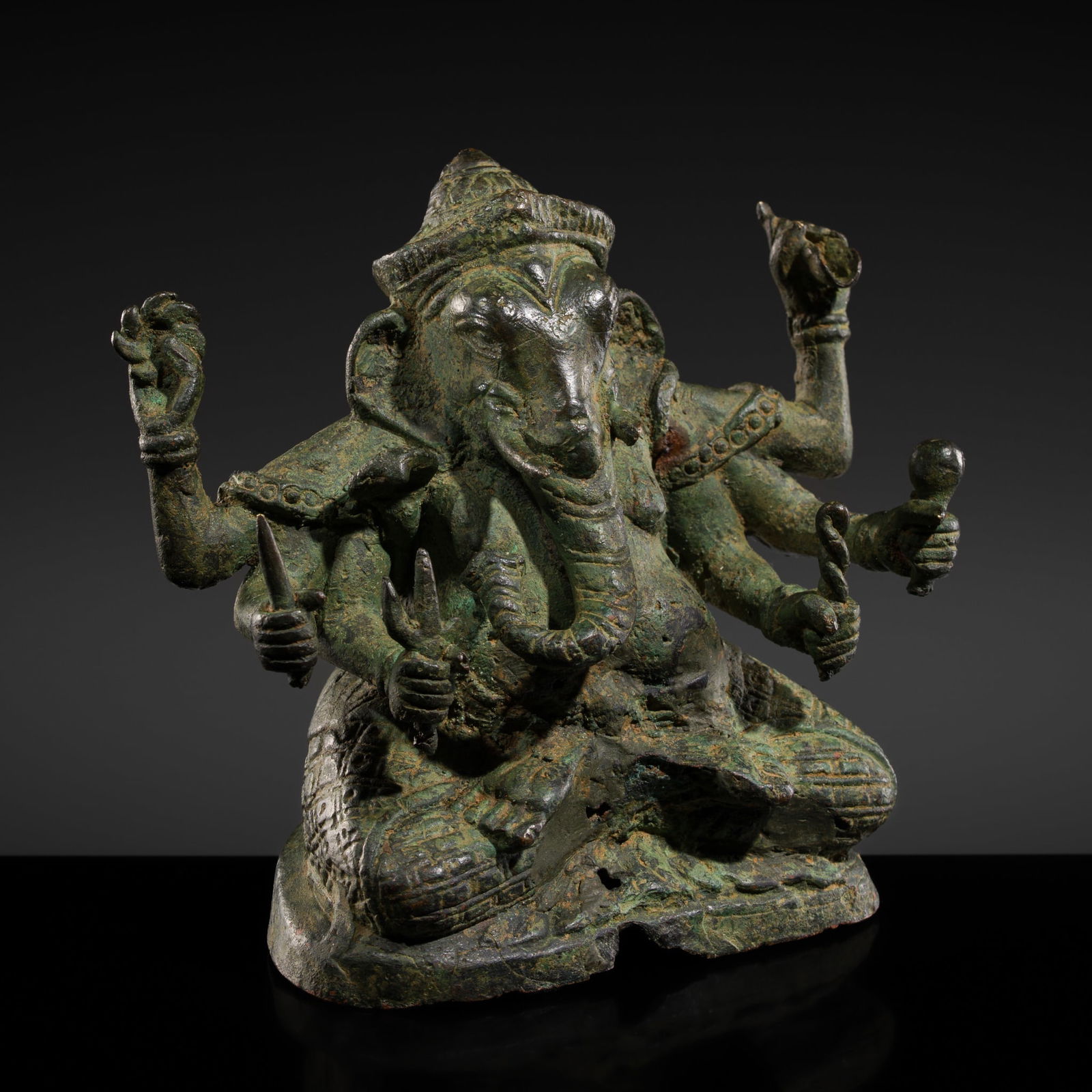 A BRONZE FIGURE OF GANESHA, ANGKOR PERIOD, BAYON STYLE, 12TH-13TH CENTURY: A BRONZE FIGURE OF GANESHA, ANGKOR PERIOD, BAYON STYLE, 12TH-13TH CENTURY Khmer Empire. Finely cast, the six-armed deity seated in dhyanasana, with multiple arms radiating from the torso, each hand be