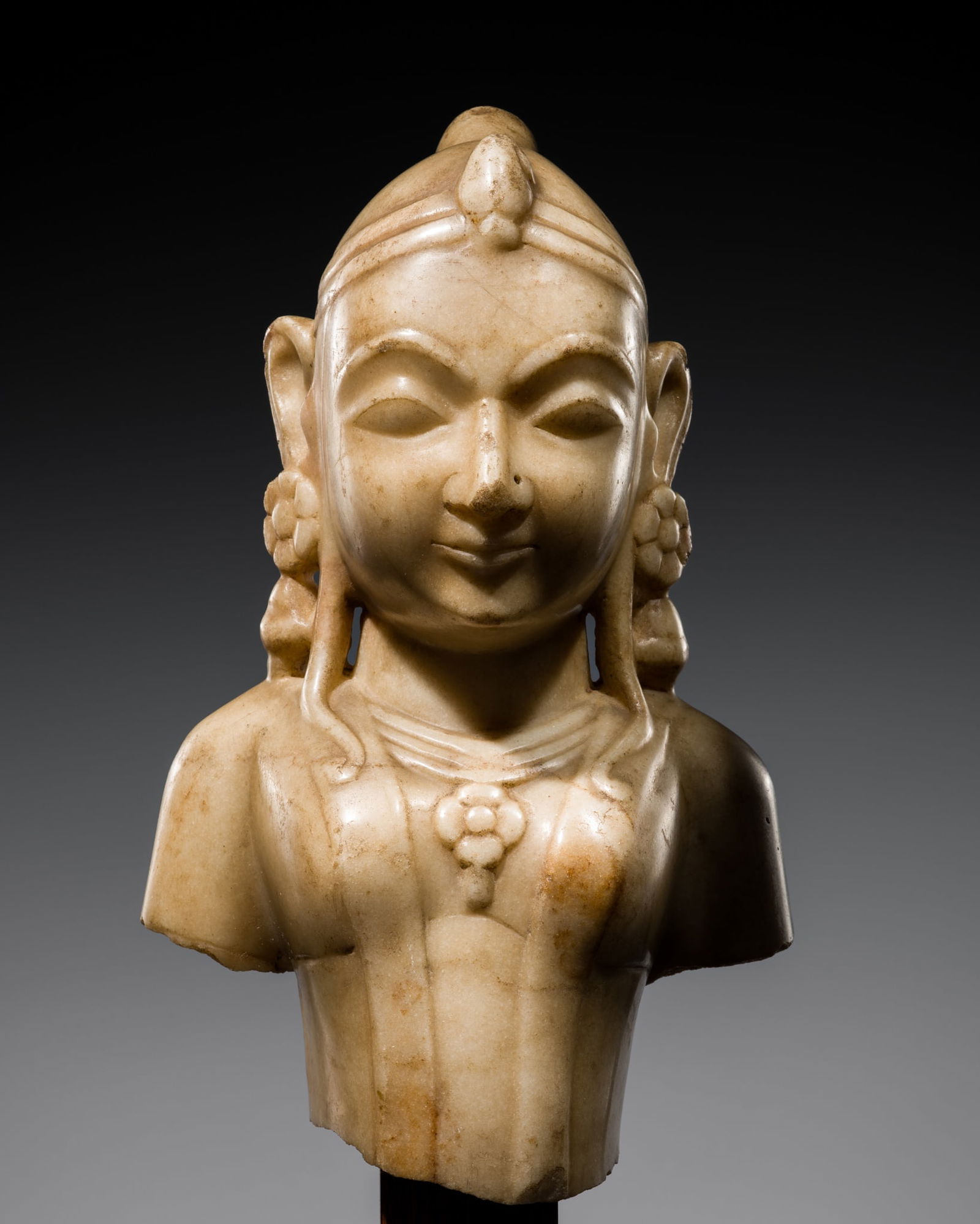 A JAIN MARBLE BUST OF A YAKSHINI, GUJARAT, 12TH-15TH CENTURY: A JAIN MARBLE BUST OF A YAKSHINI, GUJARAT, 12TH-15TH CENTURY Western India. Sensitively carved in the round, the youthful female figure clad in a diaphanous dhoti and a long scarf gracefully draped ac