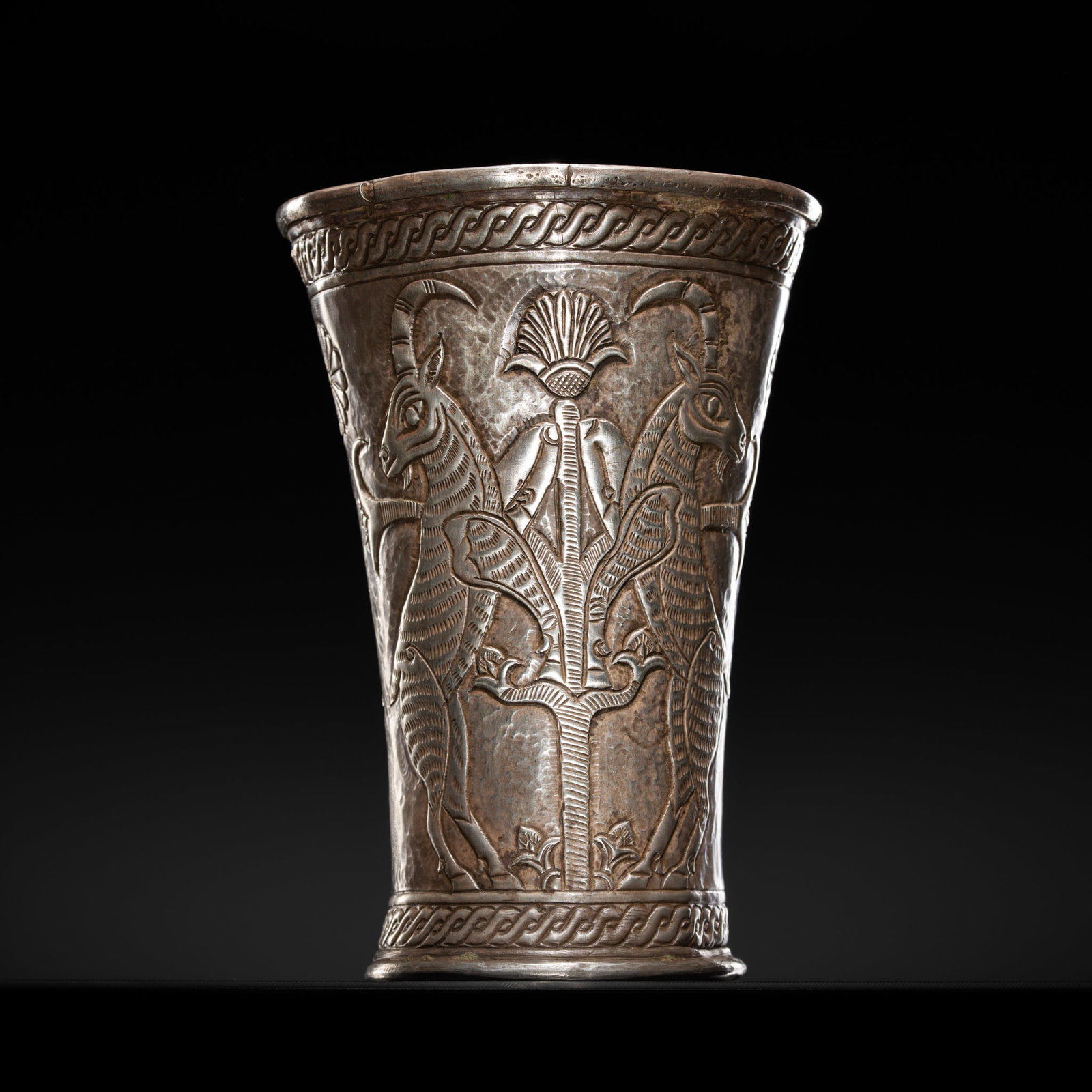 A SILVER REPOUSSÉ 'RAMPANT GOATS' BEAKER, ACHAEMENID EMPIRE, 550-330 BC: A SILVER REPOUSSÉ 'RAMPANT GOATS' BEAKER, ACHAEMENID EMPIRE, 550-330 BC Ancient Near East, possibly Crete. Of flaring form, the beaker rises from a flat foot to gently tapering sides, opening tow