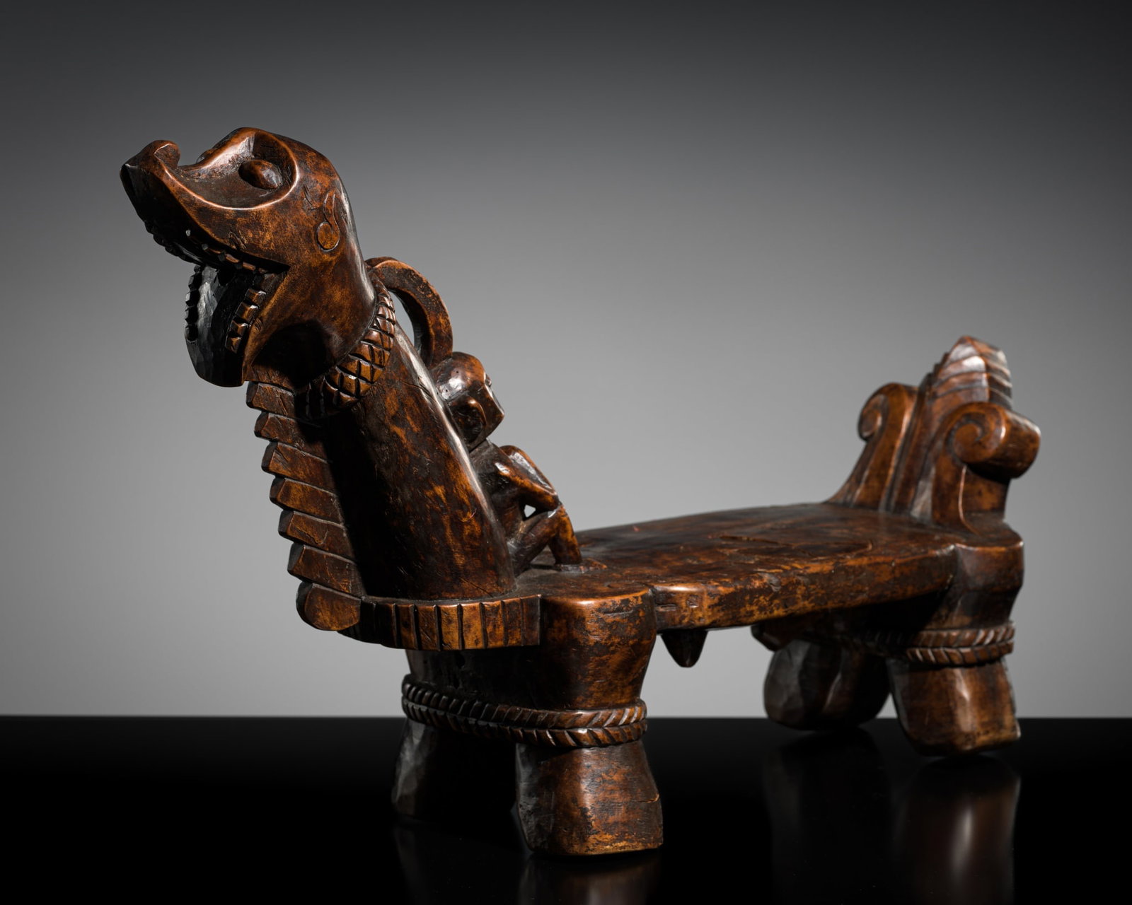 A CARVED WOOD CEREMONIAL COCONUT SCRAPER, ONO NIHA PEOPLE, SOUTHERN NIAS ISLAND: A CARVED WOOD CEREMONIAL COCONUT SCRAPER, ONO NIHA PEOPLE, SOUTHERN NIAS ISLAND Indonesia, North Sumatra, early 20th century. The low stool boldly carved in the form of a mythical animal standing four