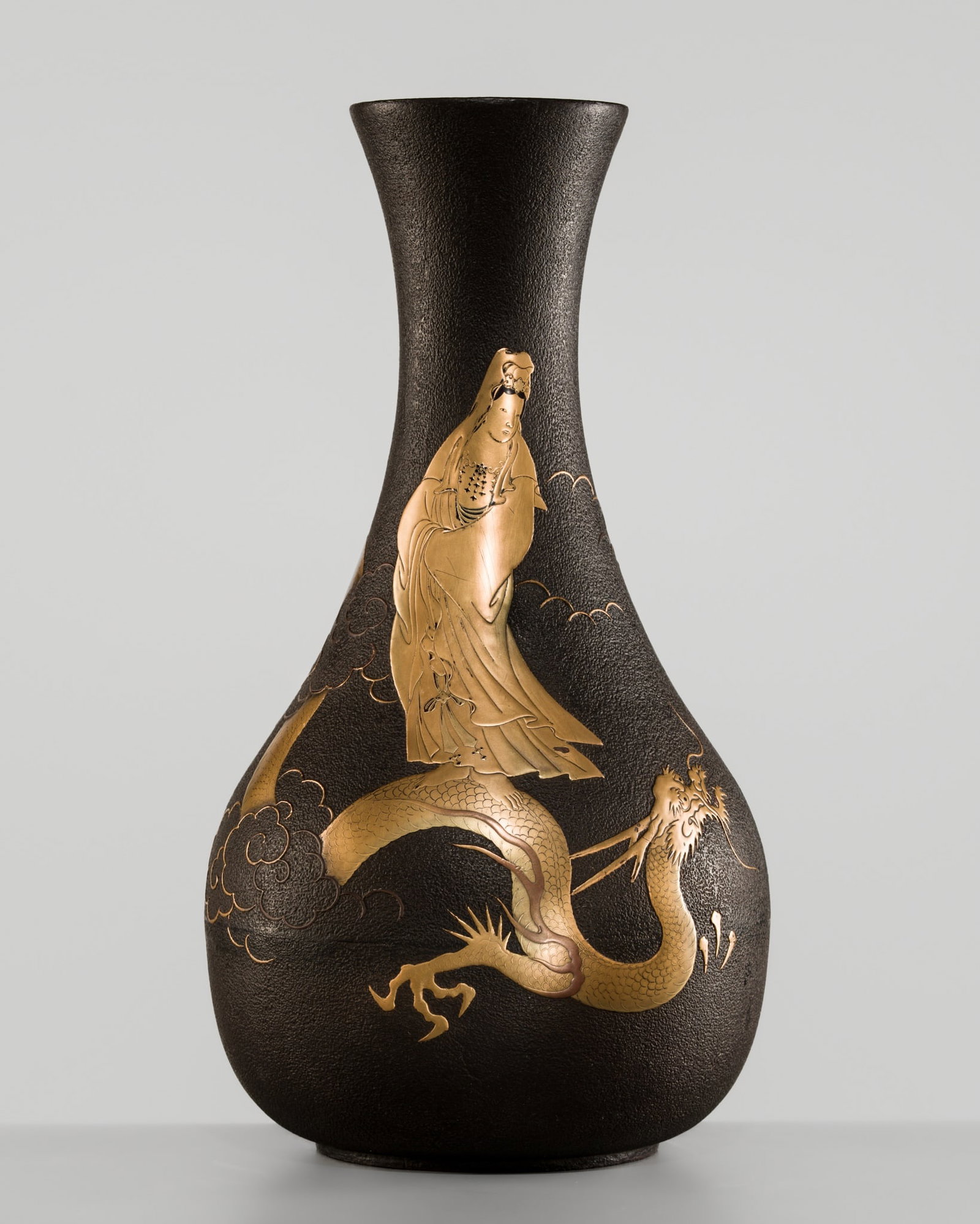 A RARE AND LARGE GOLD-LACQUERED IRON 'KANNON AND DRAGON' VASE: A RARE AND LARGE GOLD-LACQUERED IRON 'KANNON AND DRAGON' VASE Japan, Meiji period (1868-1912) Heavily cast with a pear-shaped body rising from a ring foot to a tall, flaring neck, the ishime-textured 
