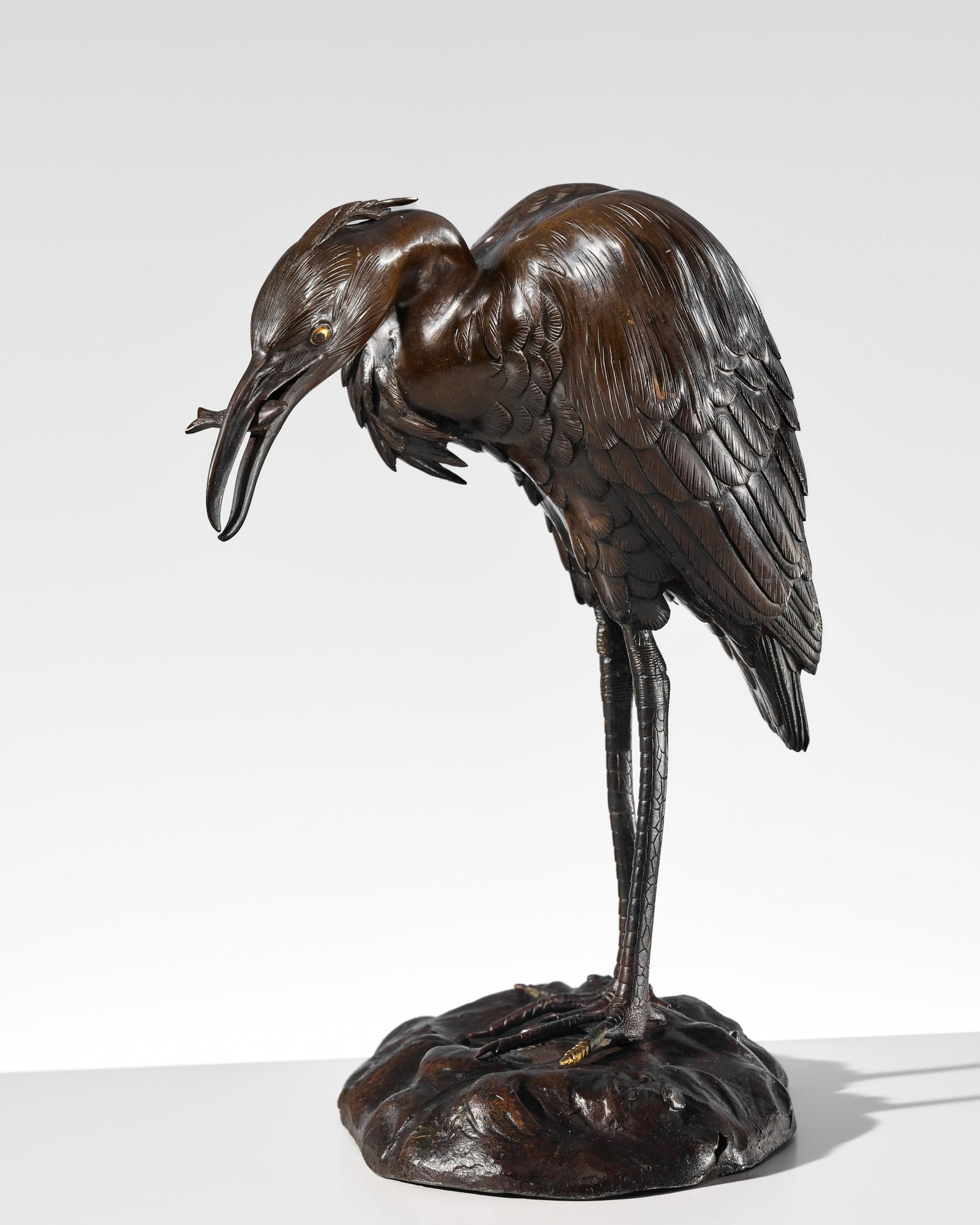 A FINE BRONZE OKIMONO OF A FISHING EGRET: A FINE BRONZE OKIMONO OF A FISHING EGRET Japan, Meiji period (1868-1912) Finely cast, the egret stands on both feet atop an oval base formed as a naturalistically rendered rocky riverbank. Its long ne
