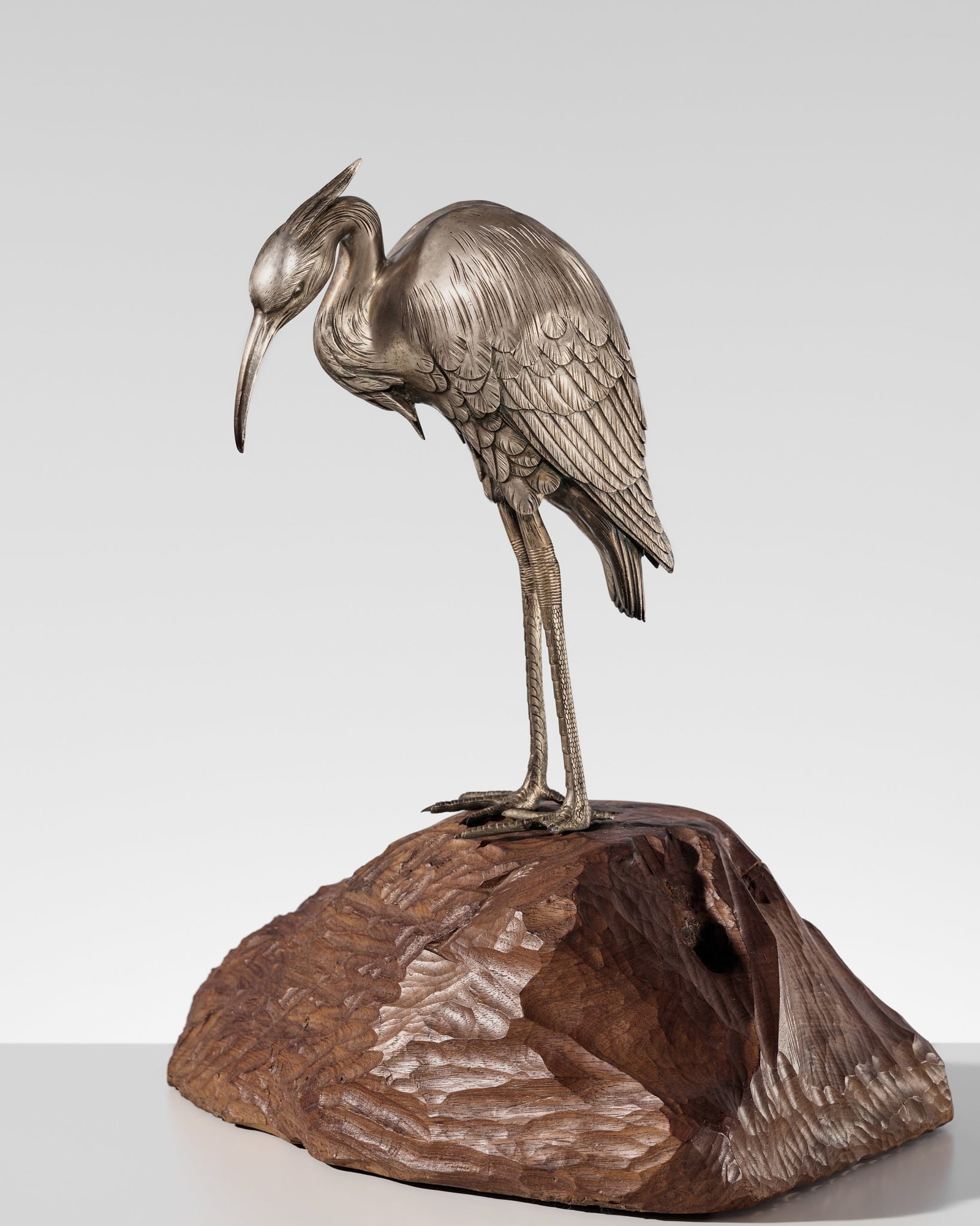 A FINE SILVERED BRONZE OKIMONO OF AN EGRET: A FINE SILVERED BRONZE OKIMONO OF AN EGRET Japan, Meiji period (1868-1912) Finely cast and silvered, the egret stands on both feet atop a large carved wood base. The bird is elegantly poised with its 