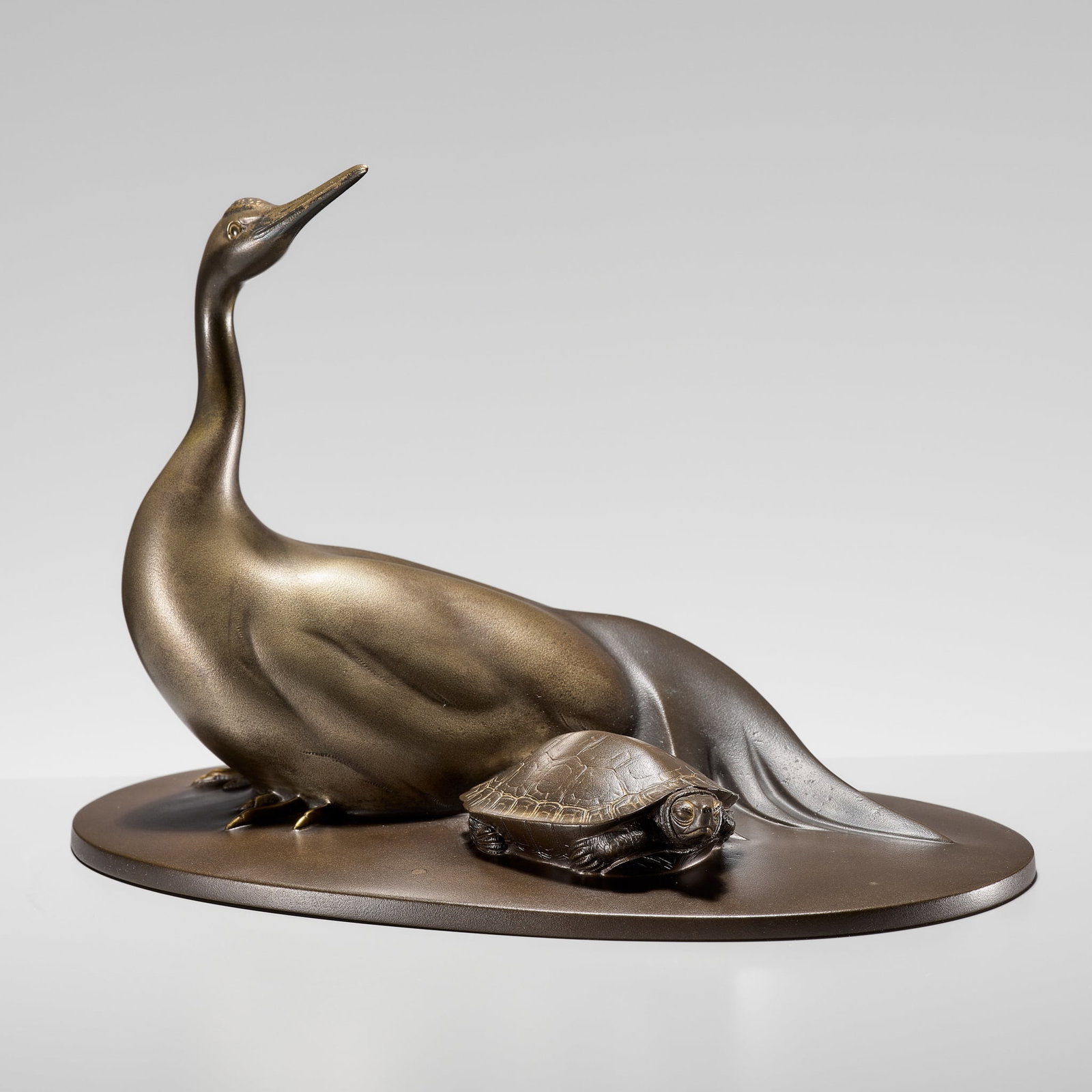 KATO TATSUO: A FINE PATINATED BRONZE OKIMONO OF A TURTLE AND CRANE: KATO TATSUO: A FINE PATINATED BRONZE OKIMONO OF A TURTLE AND CRANE By Kato Tatsuo, signed Tatsuo Japan, early 20th century, Taisho period (1912-1926) Finely cast as a recumbent crane accompanied by a