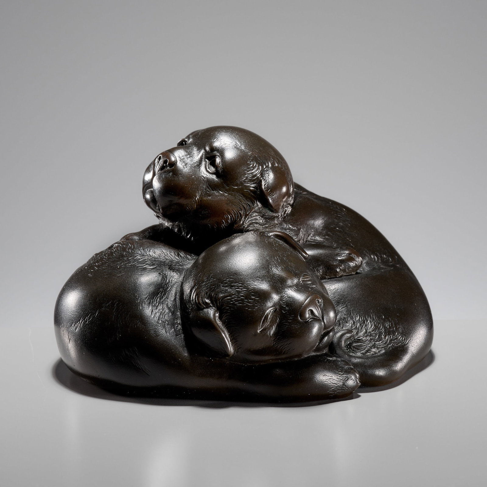 YAMAMOTO JUNMIN: A FINE BRONZE OKIMONO OF TWO SLEEPY PUPPIES: YAMAMOTO JUNMIN: A FINE BRONZE OKIMONO OF TWO SLEEPY PUPPIES By Yamamoto Junmin (1888-1962), signed Junmin in Japan, c. 1930s, Showa period (1926-1989) Finely cast as two curled up puppies, one fast a