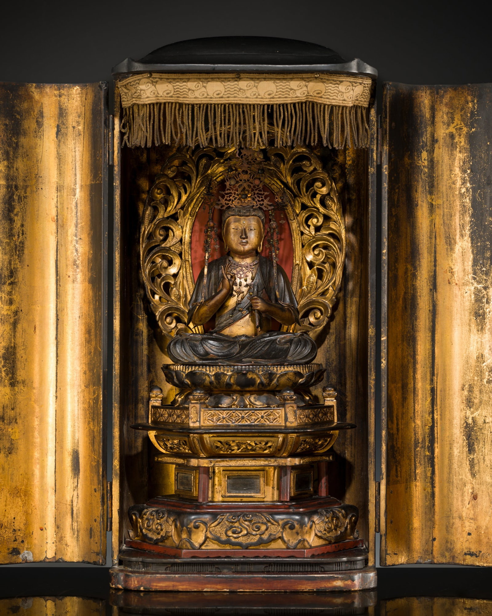 A LACQUERED WOOD ZUSHI (PORTABLE SHRINE) WITH SEATED KANNON, WITH A BUILT-IN 'ILLUMINATING LIGHT',: A LACQUERED WOOD ZUSHI (PORTABLE SHRINE) WITH SEATED KANNON, WITH A BUILT-IN 'ILLUMINATING LIGHT', 18TH CENTURY Japan, 18th century, Edo period (1615-1868) Finely carved, the figure of Kannon is shown