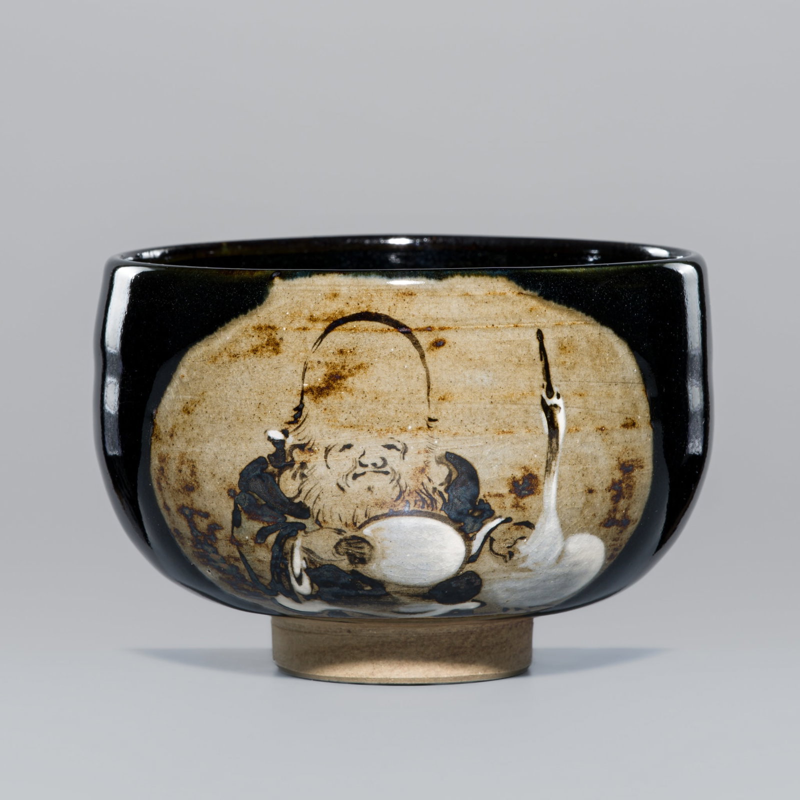 MAKUZU KOZAN I: A BLACK GLAZED STUDIO PORCELAIN 'JUROJIN AND CRANE' CHAWAN (TEA BOWL) (1 of 17)