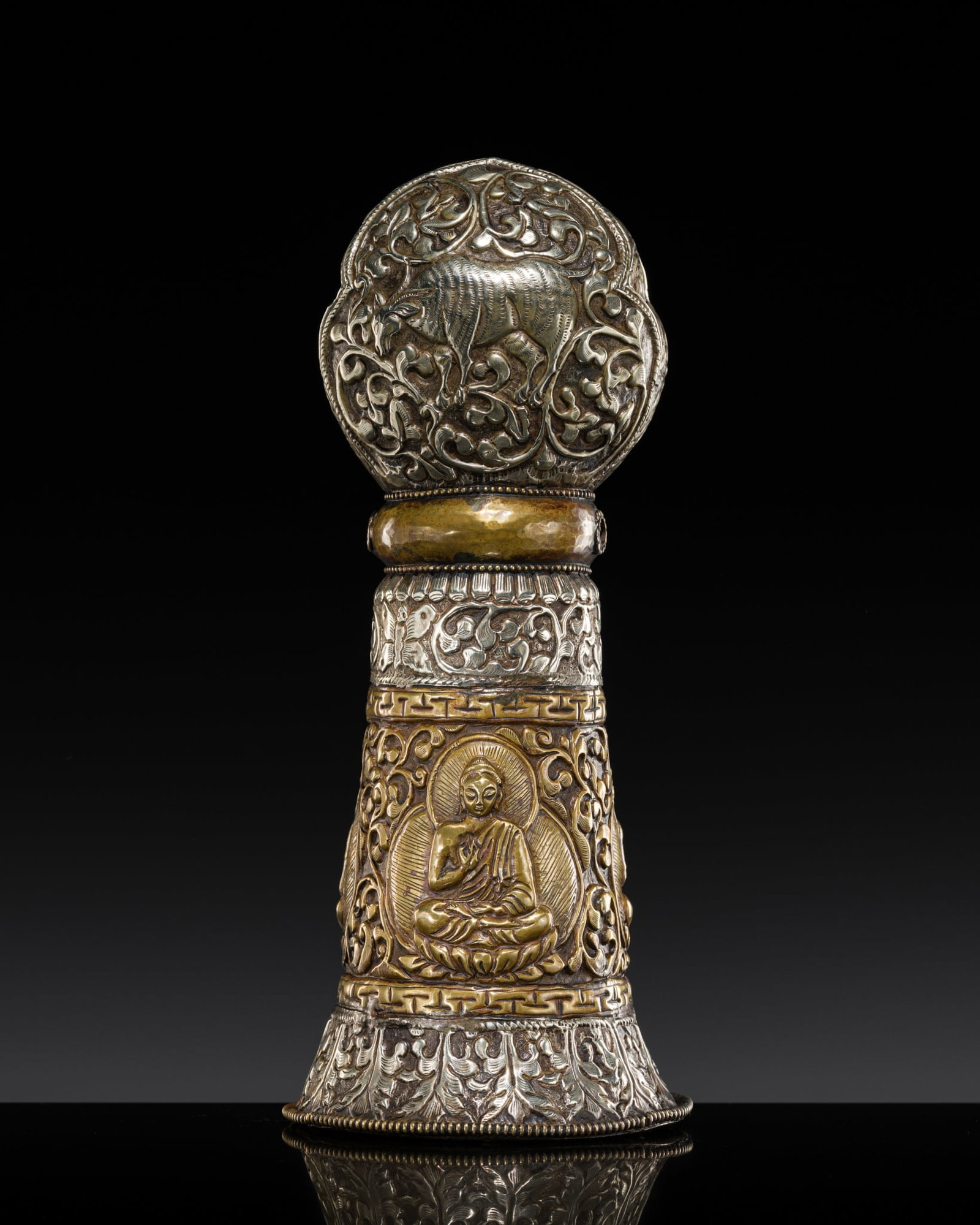 A LARGE SILVER AND BRASS REPOUSSÉ SEAL, TIBET, 19TH CENTURY: A LARGE SILVER AND BRASS REPOUSSÉ SEAL, TIBET, 19TH CENTURY Of bell-form, rising from a gently everted foot decorated with lappet-form foliage, the body centered by a band enclosing three figures