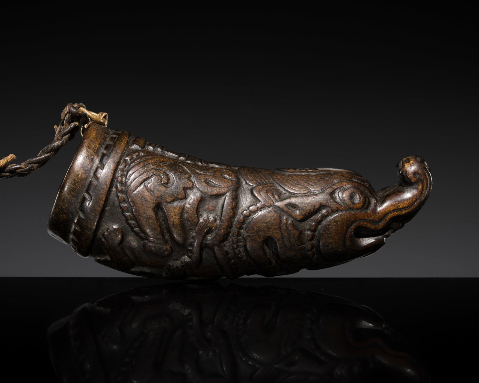 A WOOD EXORCIST'S HORN, THUN RVA, TIBET, 18TH CENTURY: A WOOD EXORCIST'S HORN, THUN RVA, TIBET, 18TH CENTURY Finely carved in low relief to depict a humanoid turtle with scaly skin centered at the belly with a large blossom, framed by a makara, its elonga