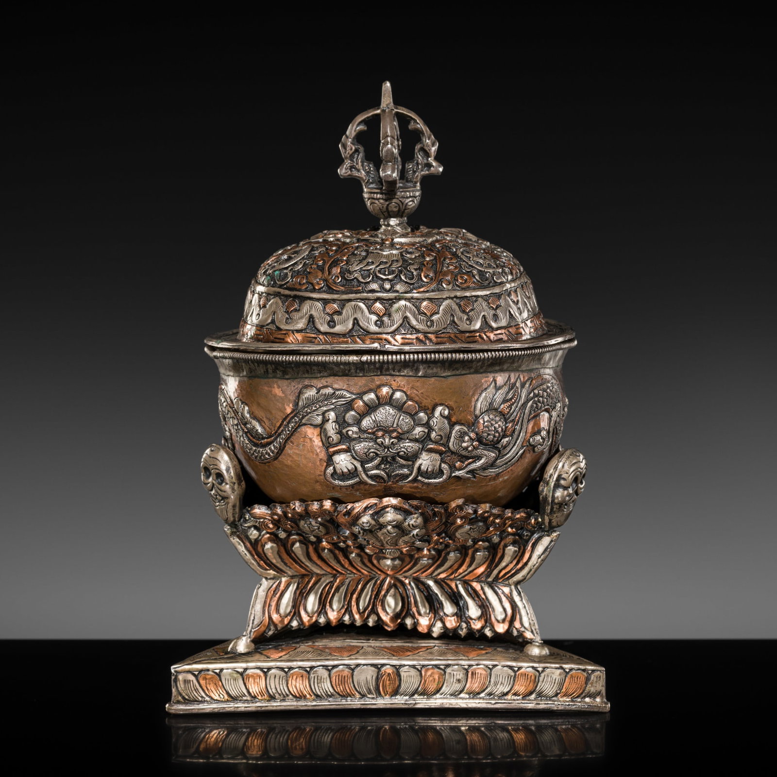 A PARCEL-COPPERED WHITE METAL REPOUSSÉ KAPALA AND STAND, TIBET, 19TH CENTURY (1 of 20)