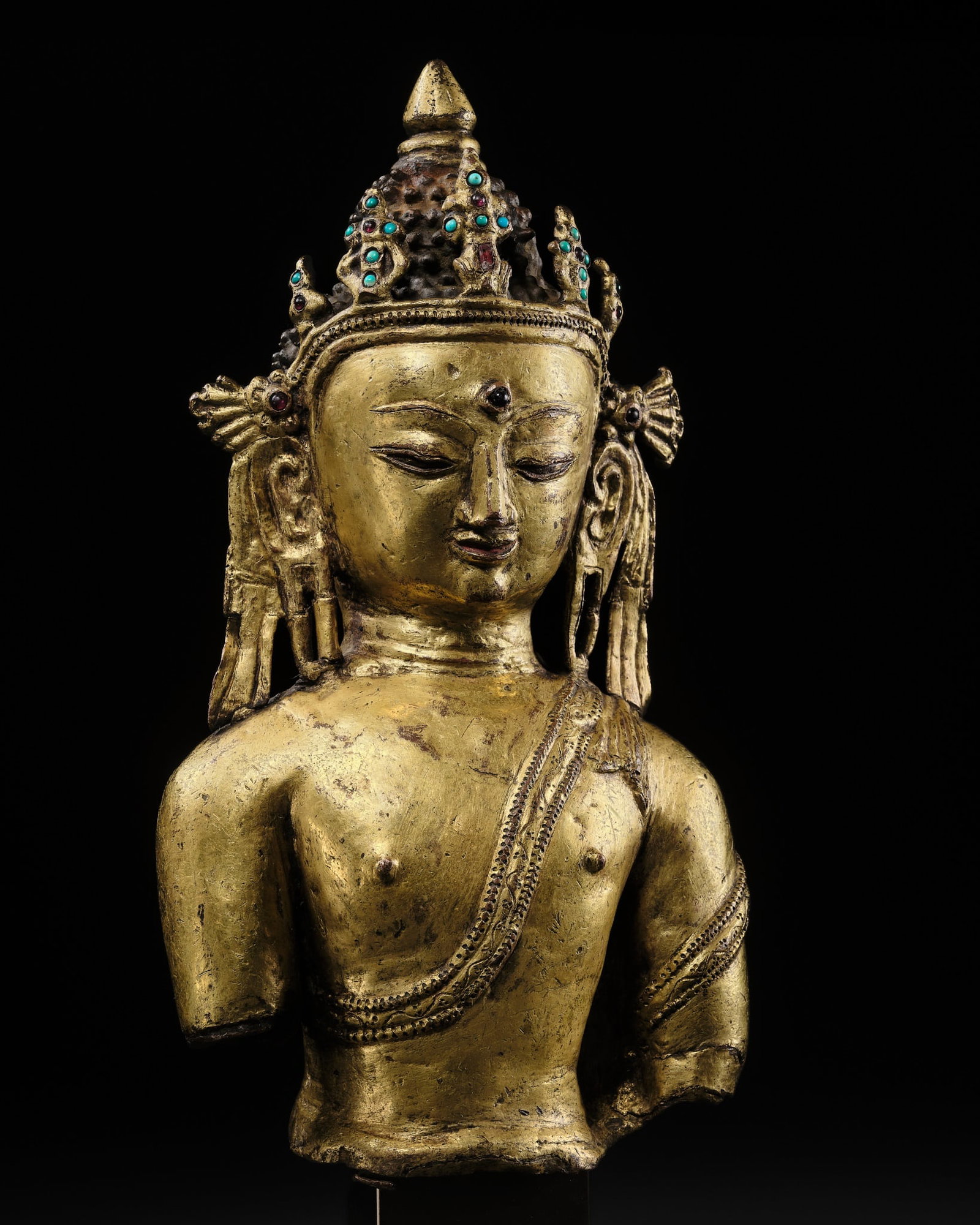 A RARE GILT-BRONZE BUST OF BUDDHA SHAKYAMUNI, EARLY MALLA PERIOD, NEPAL, 14TH-15TH CENTURY: A RARE GILT-BRONZE BUST OF BUDDHA SHAKYAMUNI, EARLY MALLA PERIOD, NEPAL, 14TH-15TH CENTURY Expert's note: The present bronze most likely once formed part of a seated figure of the Buddha Shakyamuni, o