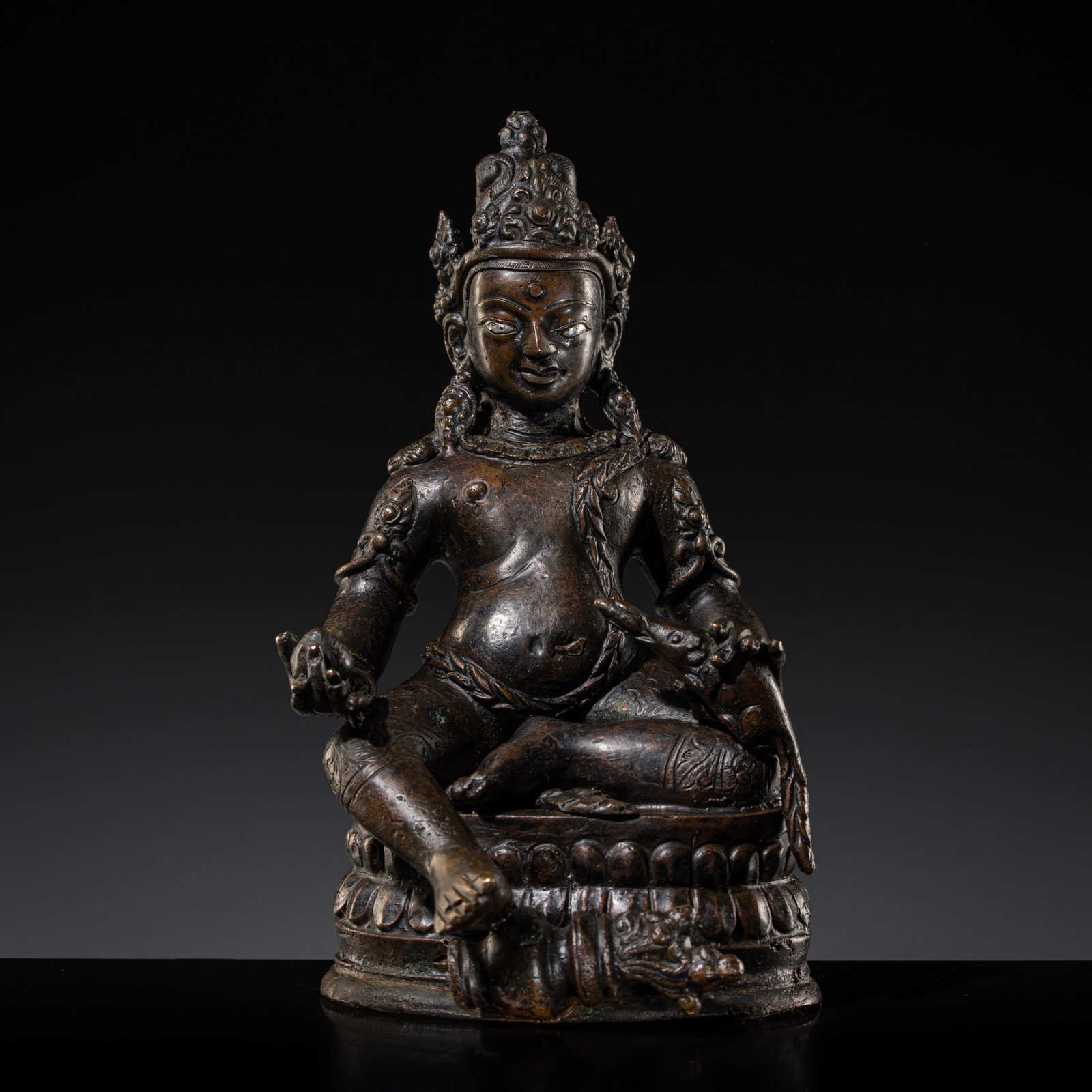 A SILVER-INLAID BRONZE FIGURE OF JAMBHALA, TIBET, 18TH-19TH CENTURY: A SILVER-INLAID BRONZE FIGURE OF JAMBHALA, TIBET, 18TH-19TH CENTURY Finely cast, the figure seated in a relaxed pose atop a double lotus base, the pendant left leg toppling over treasure pot, effectiv