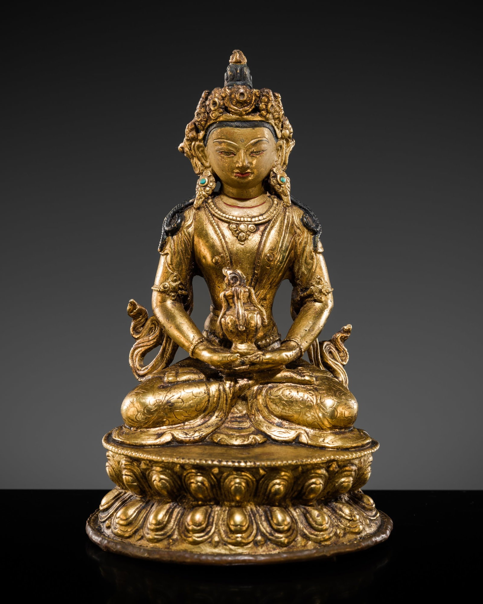 AN INLAID GILT-BRONZE FIGURE OF AMITAYUS, TIBET, 19TH-EARLY 20TH CENTURY: AN INLAID GILT-BRONZE FIGURE OF AMITAYUS, TIBET, 19TH-EARLY 20TH CENTURY Finely cast seated in dhyanasana on a double-lotus base with beaded edges, the hands lowered in dhyanamudra and supporting a va