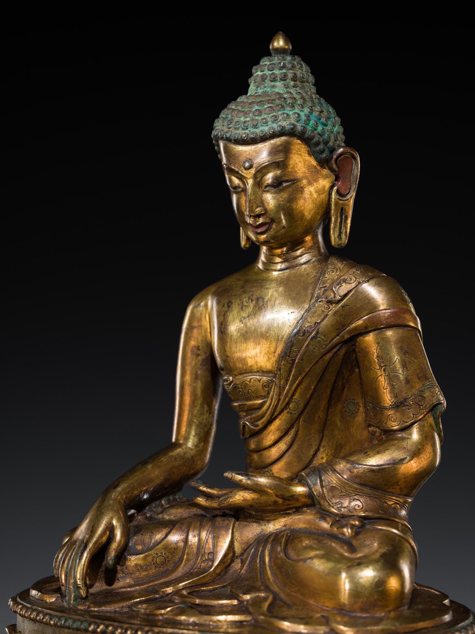 A GILT-BRONZE OF BUDDHA SHAKYAMUNI, TIBETAN-CHINESE, 19TH-FIRST HALF OF 20TH CENTURY: A GILT-BRONZE OF BUDDHA SHAKYAMUNI, TIBETAN-CHINESE, 19TH-FIRST HALF OF 20TH CENTURY Finely cast, seated in dhyanasana atop a double lotus throne with a beaded edge, the back incised with scrolling vi