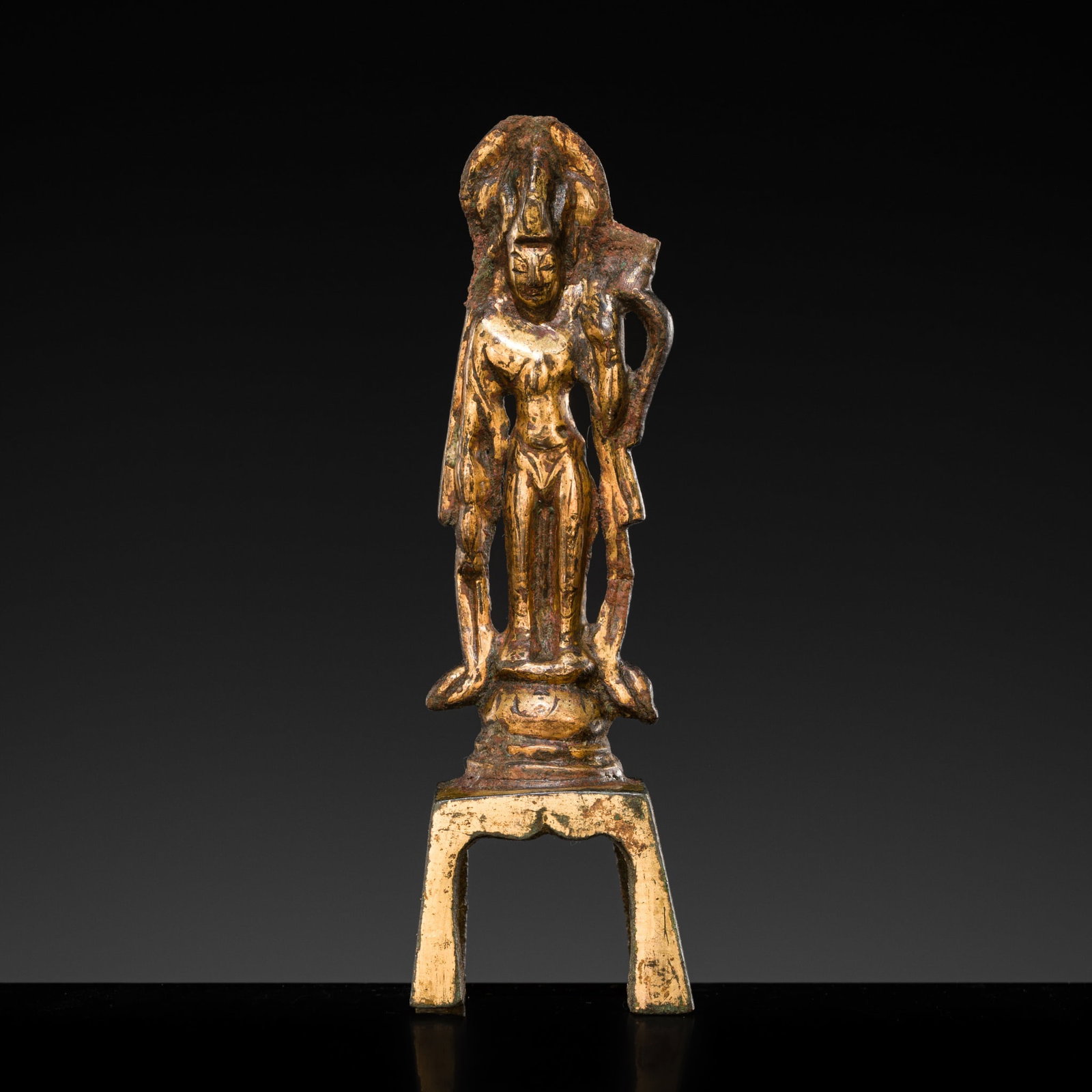 A SMALL GILT-BRONZE FIGURE OF A BODHISATTVA, TANG DYNASTY: A SMALL GILT-BRONZE FIGURE OF A BODHISATTVA, TANG DYNASTY China, 618-907. Finely cast, standing in slight tribhanga on a circular lotus pedestal raised on an integral four-legged stand, with a kamandu