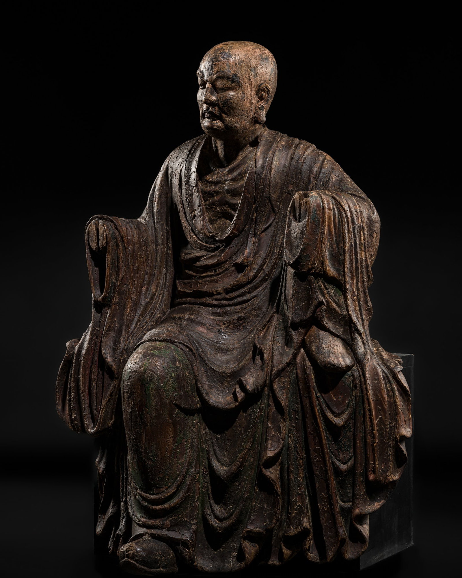 A LARGE POLYCHROME WOOD FIGURE OF BODHIDHARMA AFTER HIS RESURRECTION, EARLY MING DYNASTY: A LARGE POLYCHROME WOOD FIGURE OF BODHIDHARMA AFTER HIS RESURRECTION, EARLY MING DYNASTY China, circa 14th-15th century. Finely carved to depict Damo (Bodhidharma) after he rose from the dead as revea
