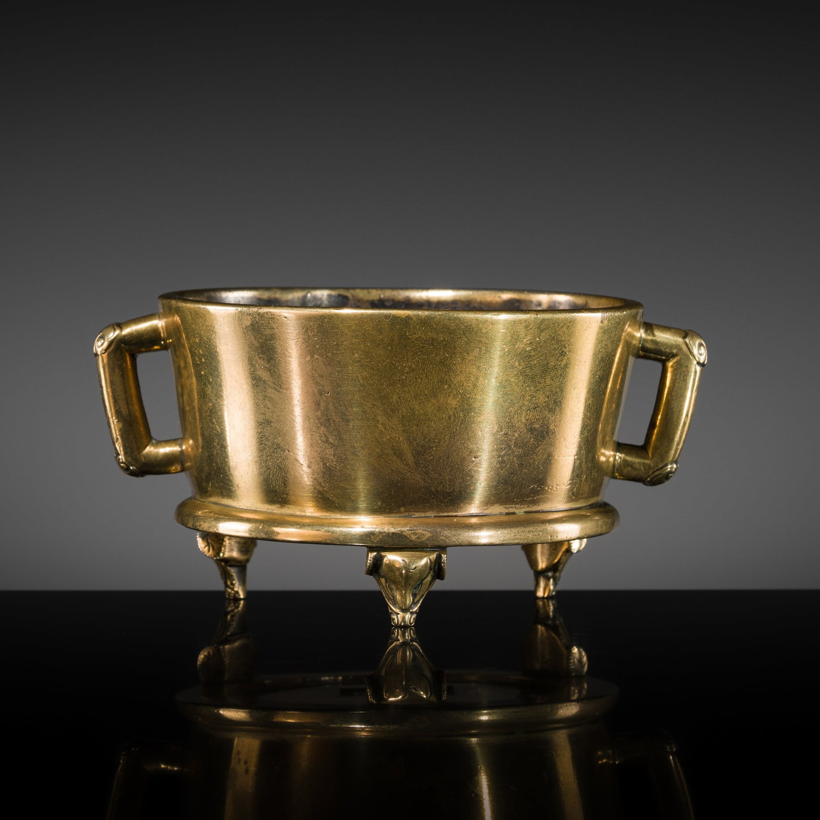 A BRONZE TWO-HANDLED TRIPOD CENSER, 17TH CENTURY: A BRONZE TWO-HANDLED TRIPOD CENSER, 17TH CENTURY China. The censer is cast with a pair of angular loop form loop handles with ruyi-head capped corners and is supported on three elephant-head feet. The