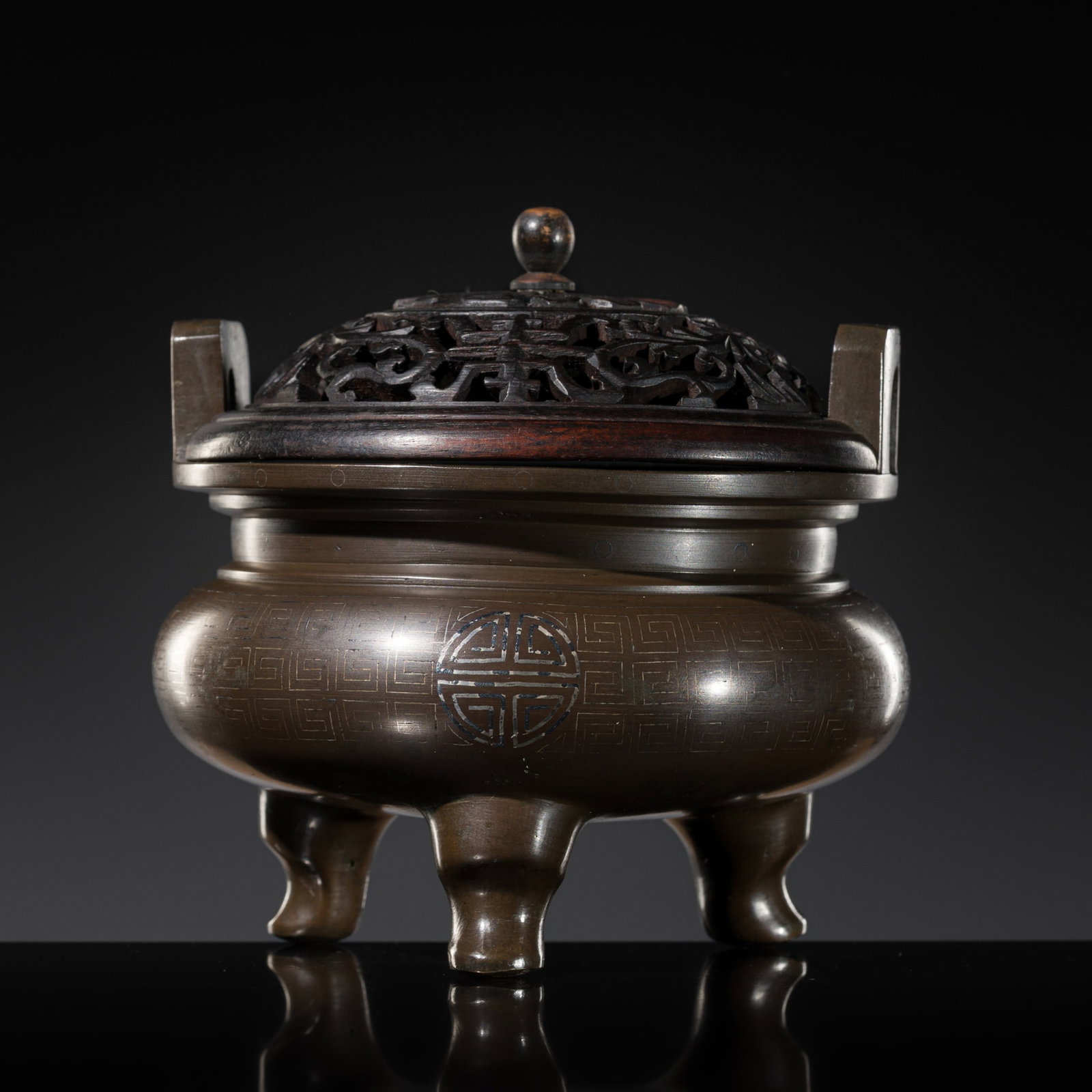 A SILVER WIRE-INLAID BRONZE TRIPOD 'LONGEVITY' CENSER, SHISOU MARK, 17TH-18TH CENTURY: A SILVER WIRE-INLAID BRONZE TRIPOD 'LONGEVITY' CENSER, SHISOU MARK, 17TH-18TH CENTURY China. The compressed globular body supported on three cabriole legs, set with two upright U-Form handles, incised