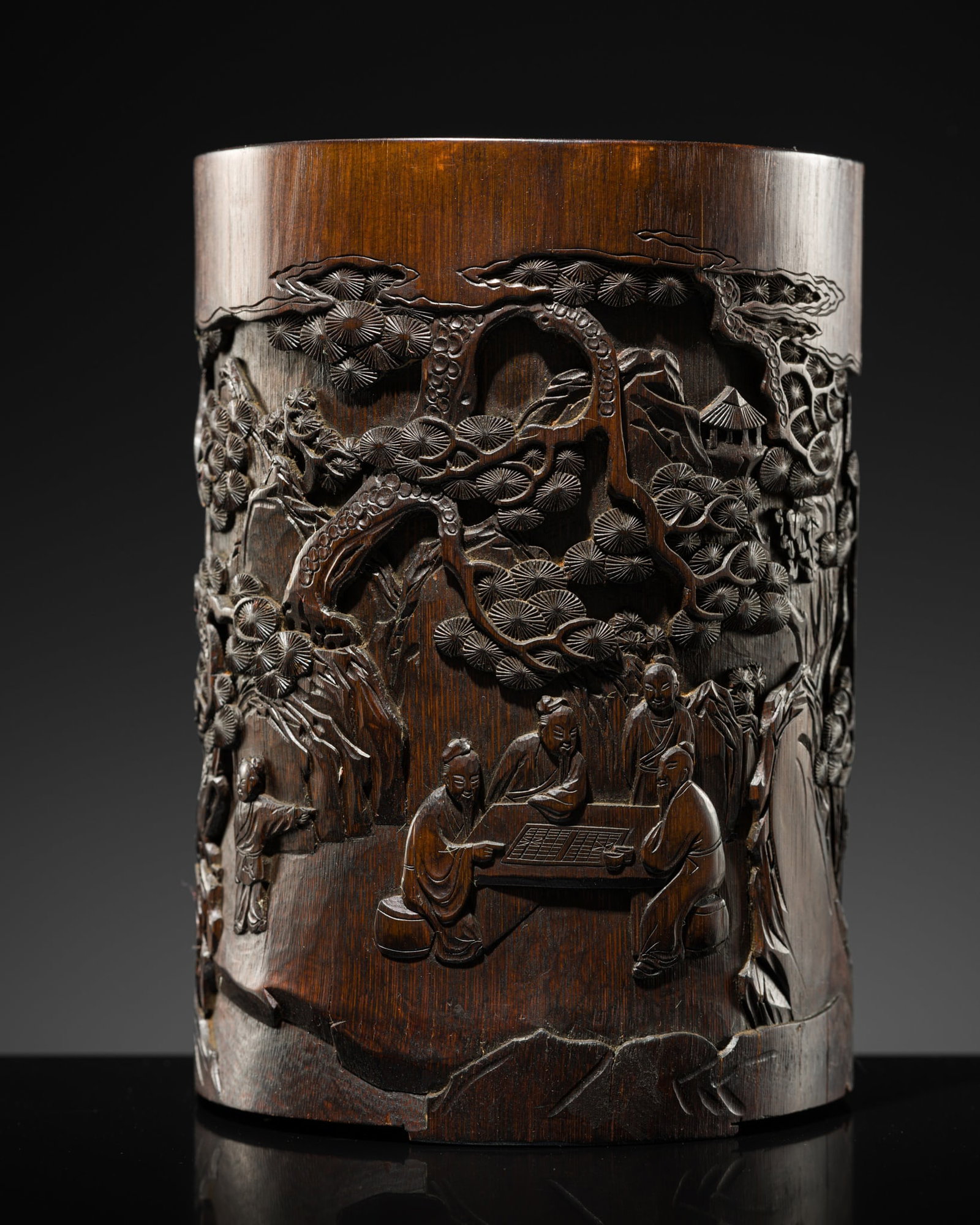 AN INSCRIBED BAMBOO 'WEIQI PLAYERS' BRUSH POT, BITONG, DATED 1853: AN INSCRIBED BAMBOO 'WEIQI PLAYERS' BRUSH POT, BITONG, DATED 1853 China. The cylindrical pot finely carved in sunken relief with scholars playing weiqi in a mountain landscape framed by pine trees, wh