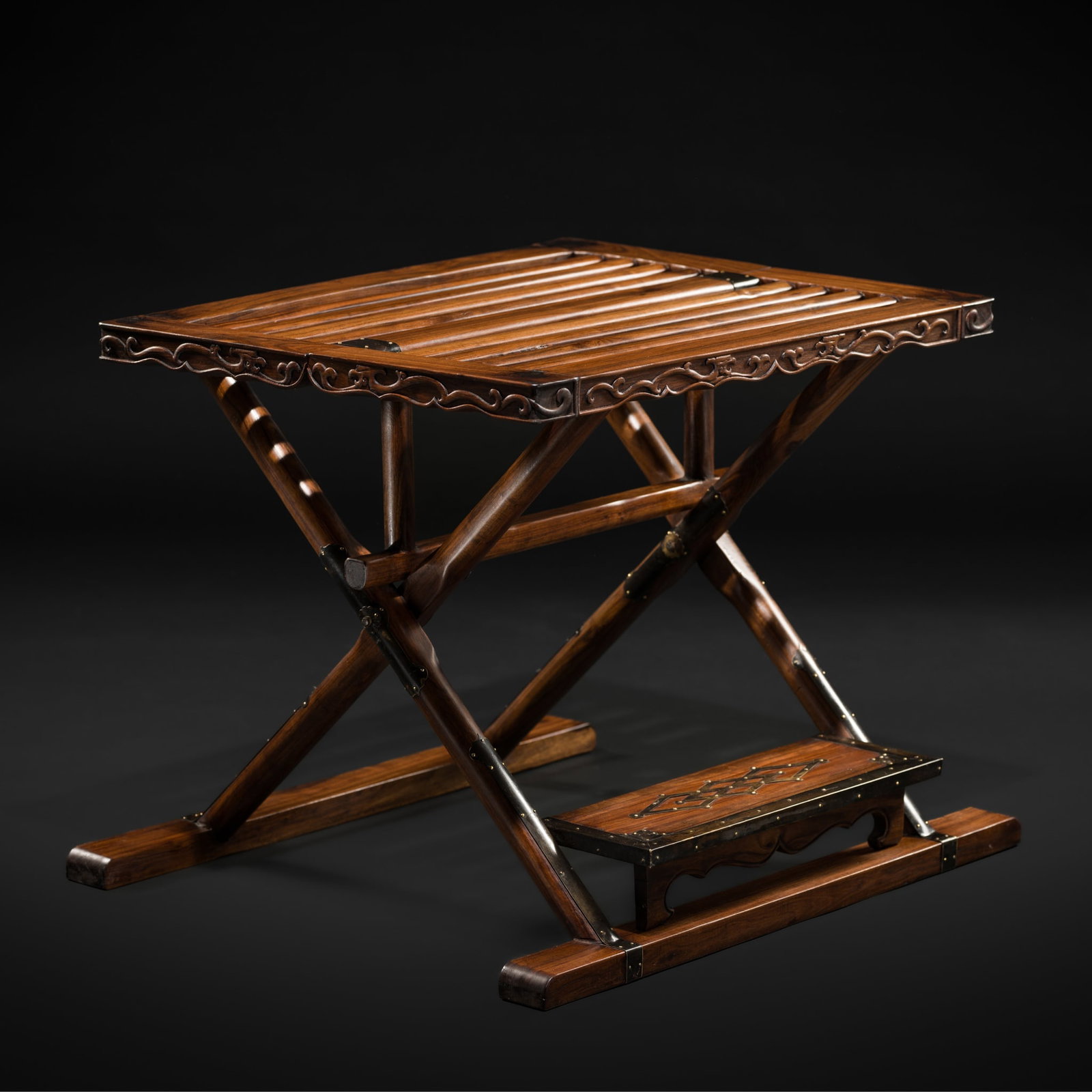 A RARE HUANGHUALI FOLDING STOOL, 19TH CENTURY: A RARE HUANGHUALI FOLDING STOOL, 19TH CENTURY China. The slatted seat is set between front and back rails carved with a pair of chilong, the whole is raised on hinged round-section legs joined by flat