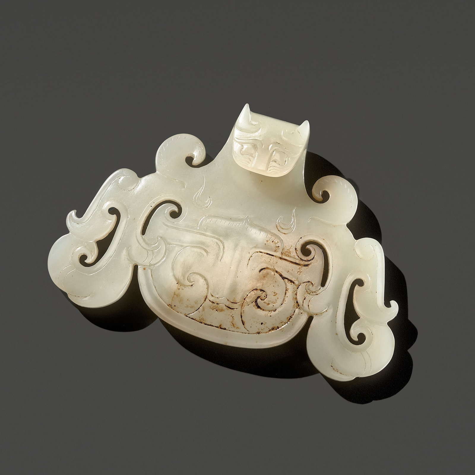 A RARE WHITE JADE 'DRAGON' BELT HOOK, WARRING STATES PERIOD: † A RARE WHITE JADE 'DRAGON' BELT HOOK, WARRING STATES PERIOD China, 475-221 BC. The belt hook finely carved and pierced with a hook in shape of a dragon head and shaft with cloud-shaped scrolls