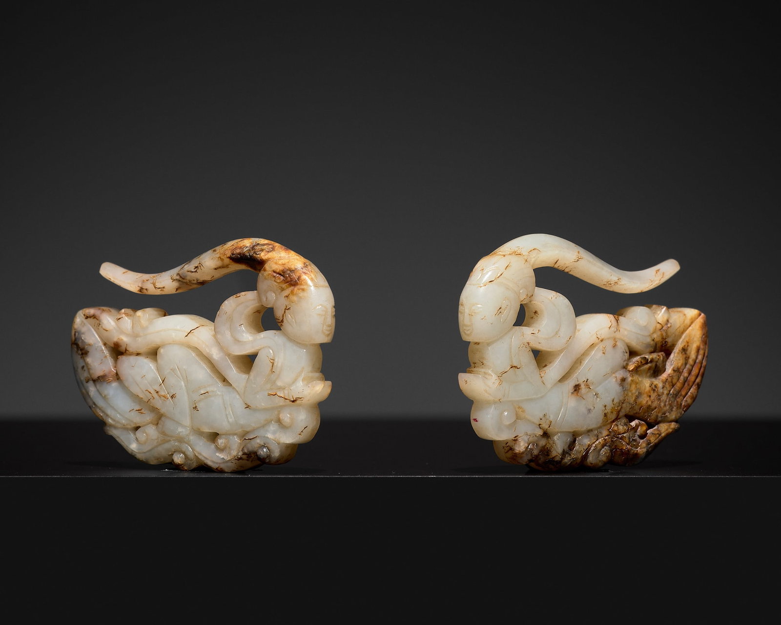 A PAIR OF WHITE AND BROWN JADE 'APSARA' EARRINGS, TANG DYNASTY: † A PAIR OF WHITE AND BROWN JADE 'APSARA' EARRINGS, TANG DYNASTY Published & Exhibited: Alvin Lo Oriental Art, Spring Exhibition, 2004, no. 15. China, 618-907. Each of flattened form, carved